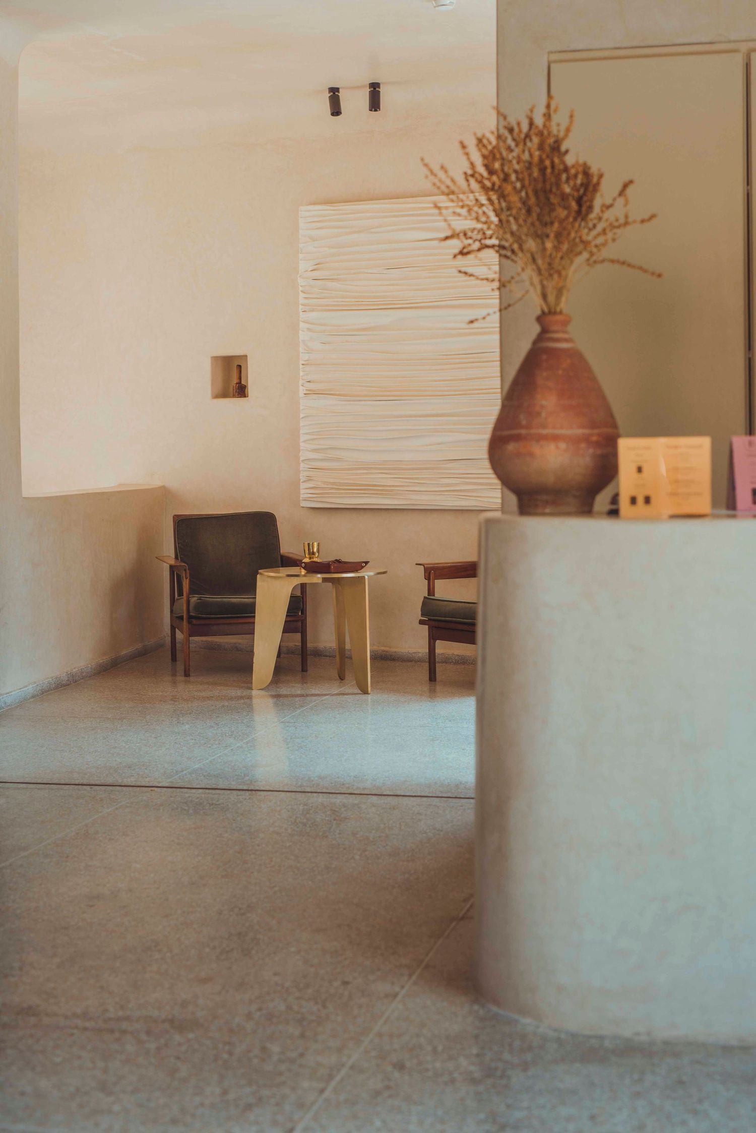 Modern minimalist living room with dried floral arrangement and curved walls.
