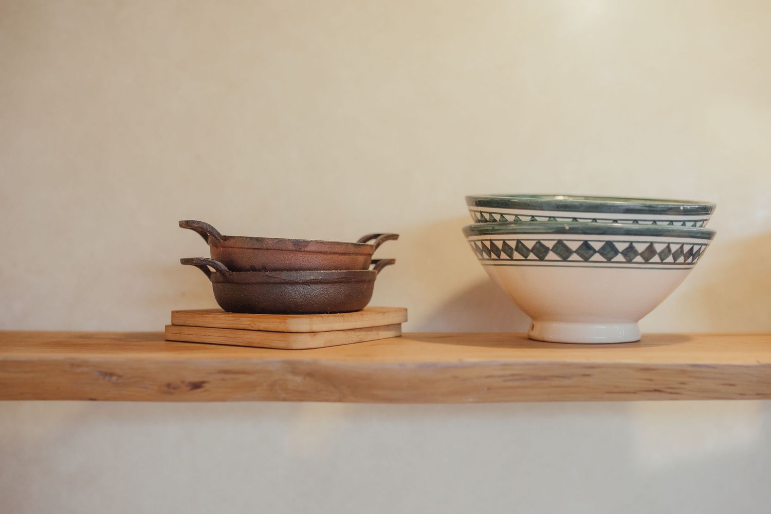 Rustic wooden shelf displaying ceramic bowls and plates in minimal arrangement.