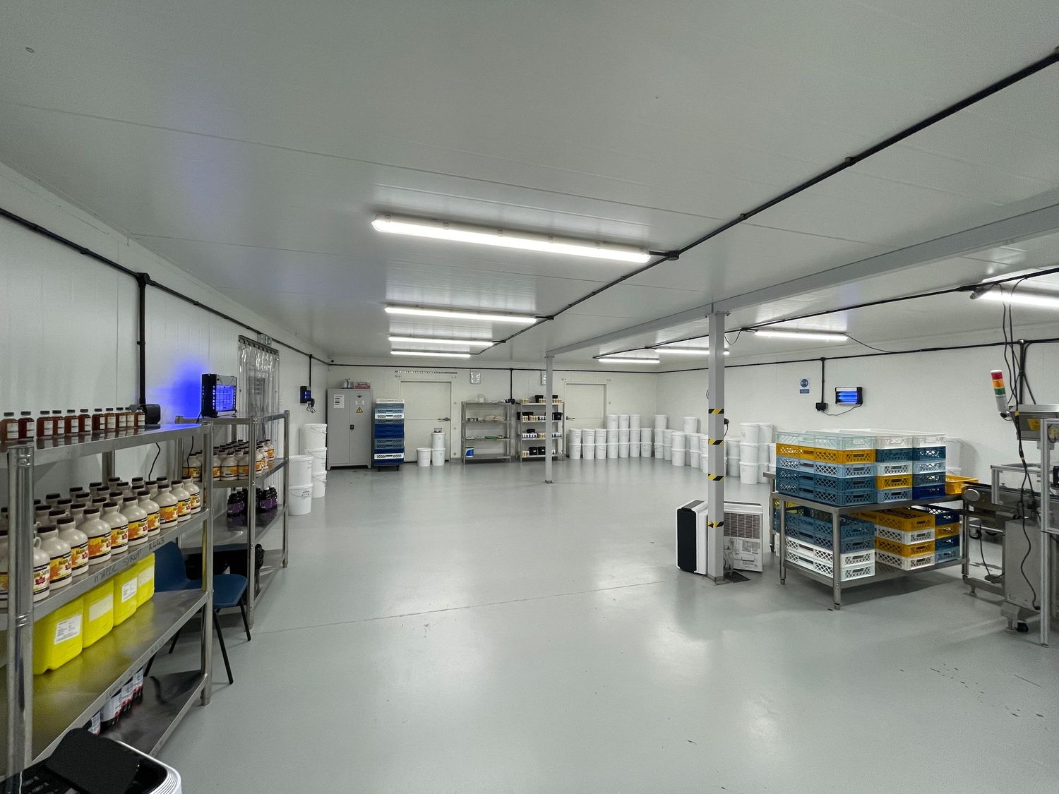 A white laboratory hallway with medical research equipment and fluorescent lighting extends into the distance.