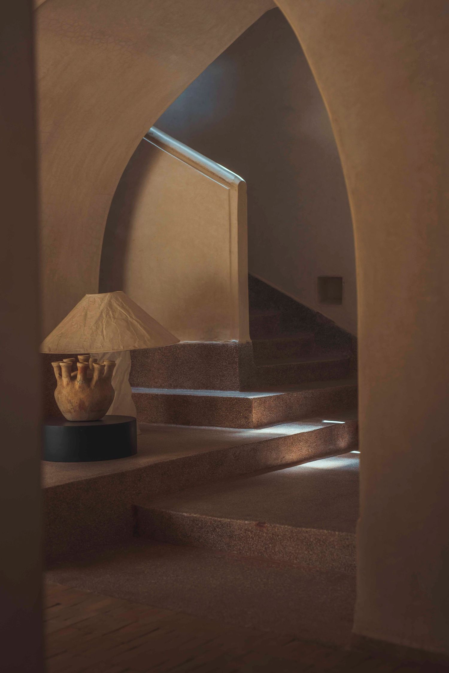 Moody archway interior with stone steps and decorative lamp creating atmospheric lighting.
