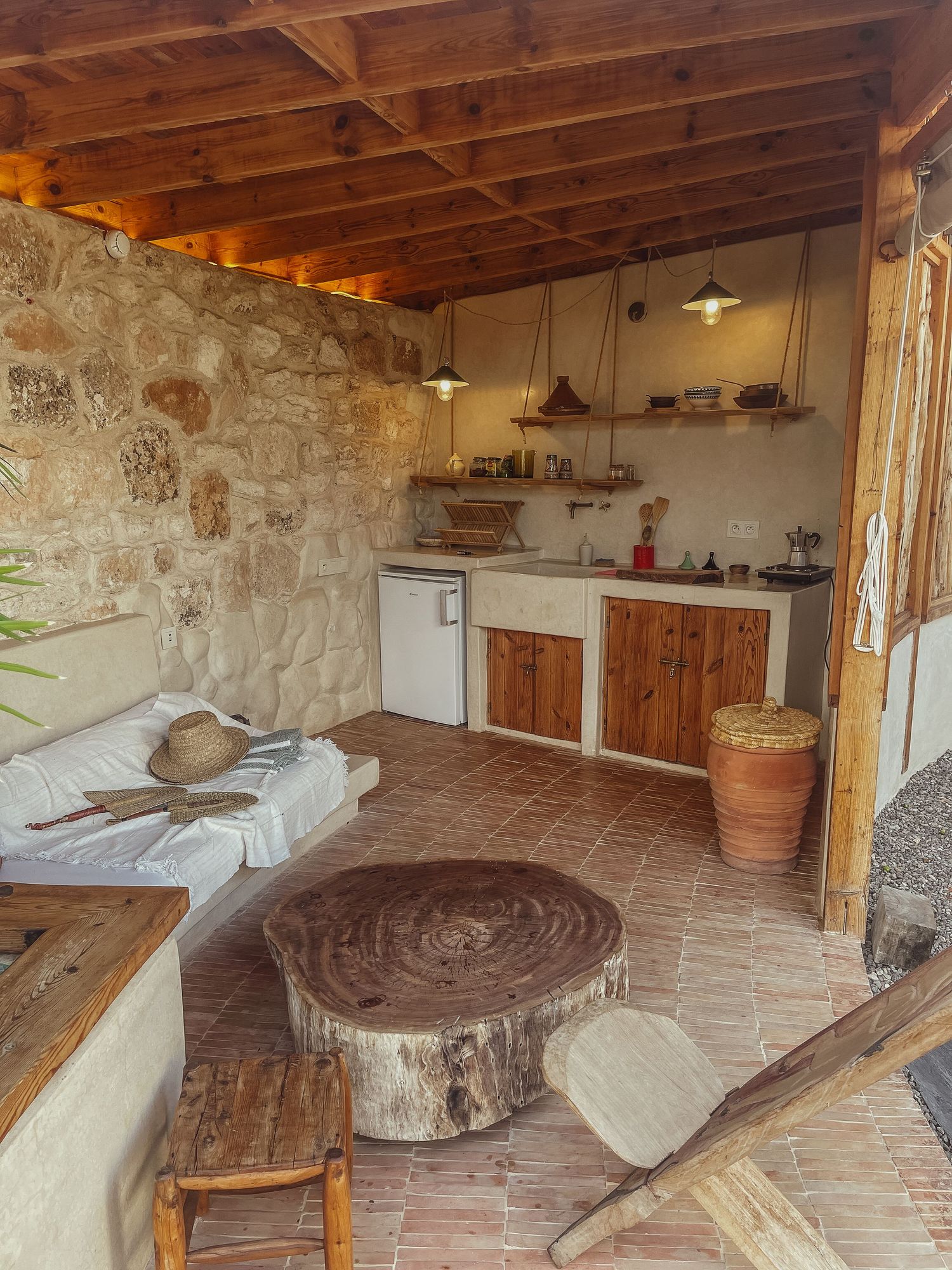 Rustic kitchen interior with stone walls, wooden counters and a tree stump coffee table.