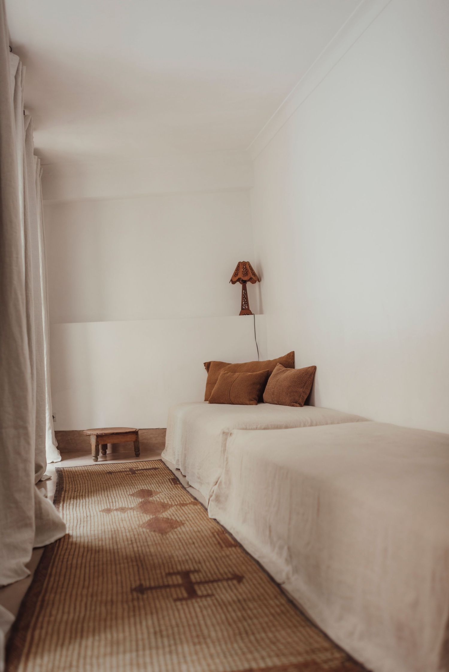 Minimalist bedroom with white walls, brown cushions, and built-in bed platform.