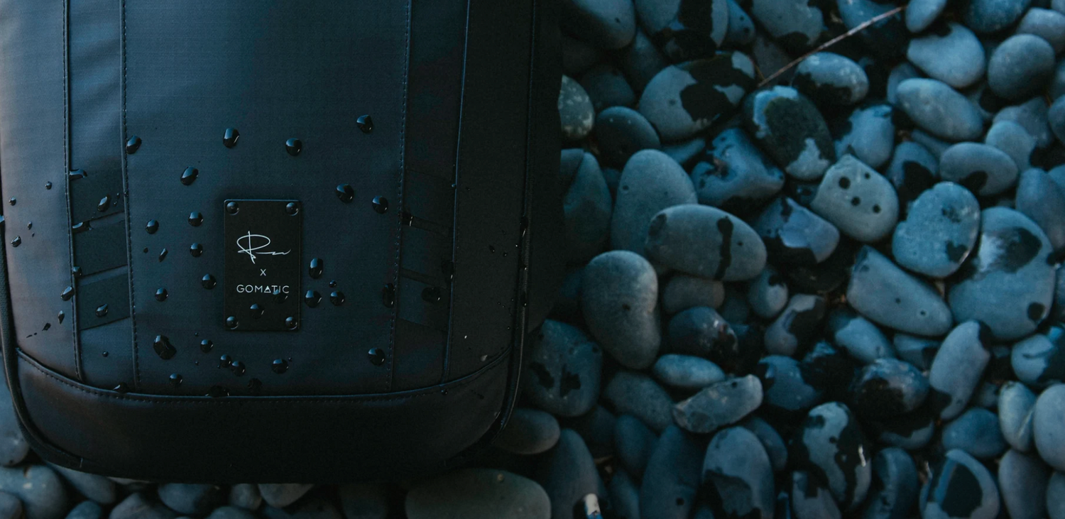 Close-up of black backpack detail against blue-lit stones or pebbles.