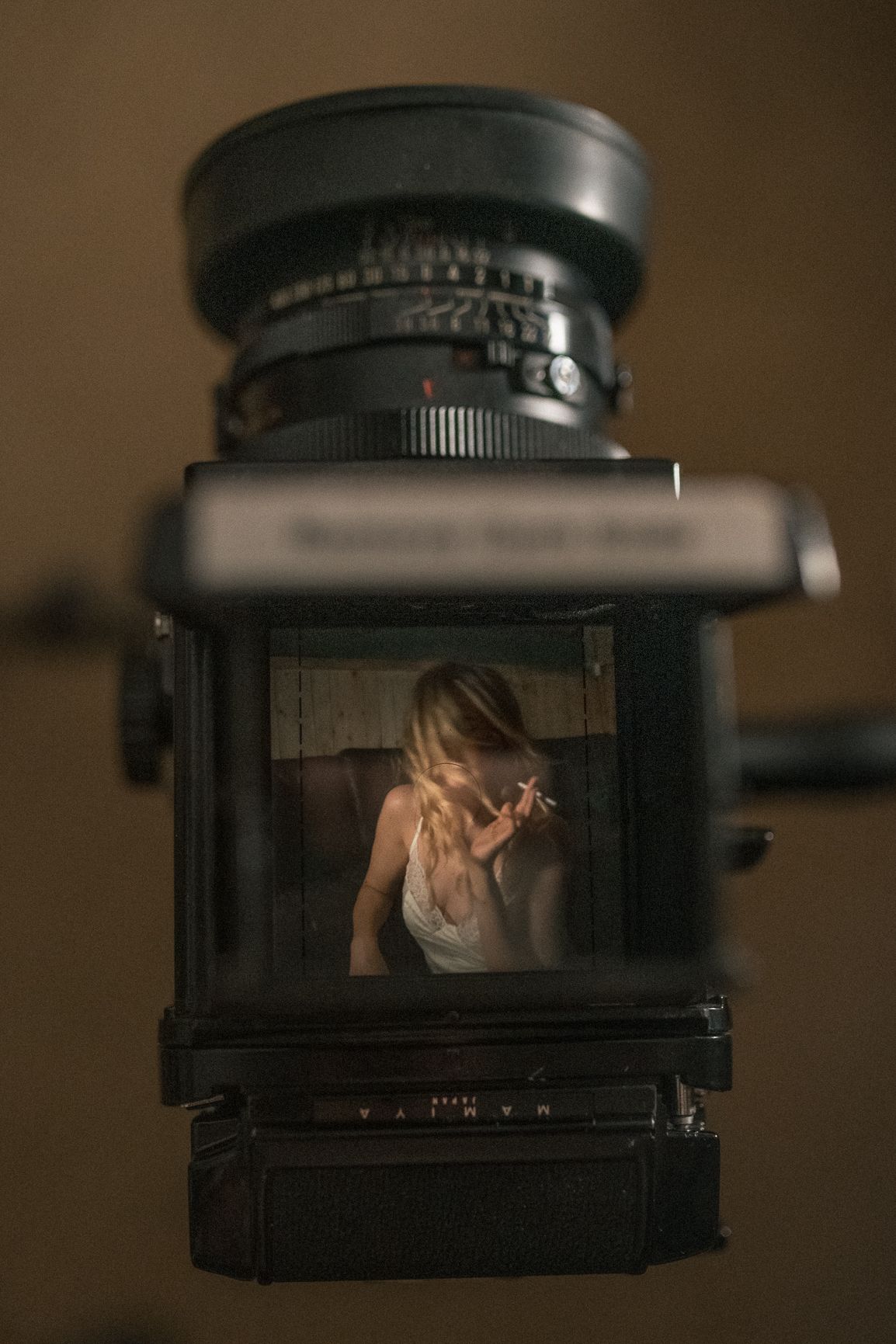 A vintage medium format camera viewfinder shows a soft, dreamy scene through its rectangular frame in moody lighting.