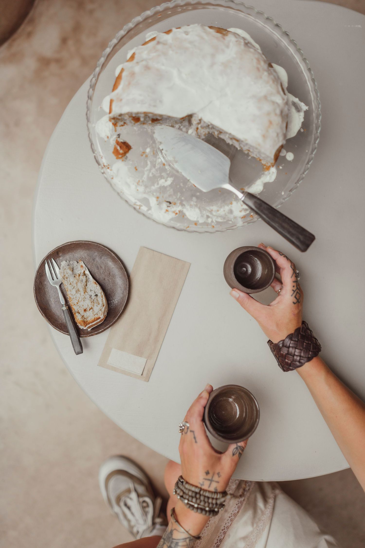 Hands frosting chocolate cupcakes with white cream and placing them on a white serving plate.