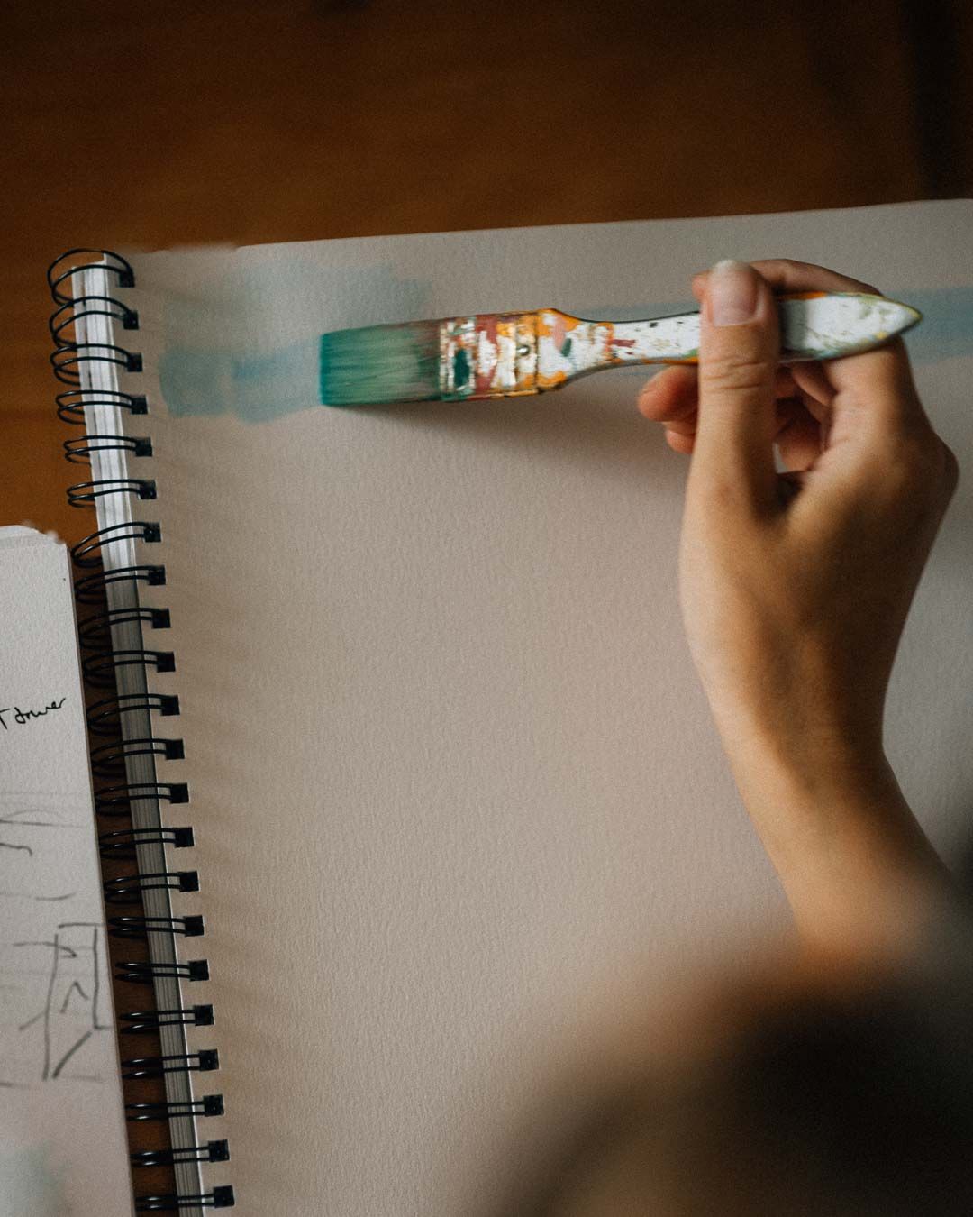 A hand drawing in a spiral notebook with a pencil, captured in sequential frames showing the sketching process.