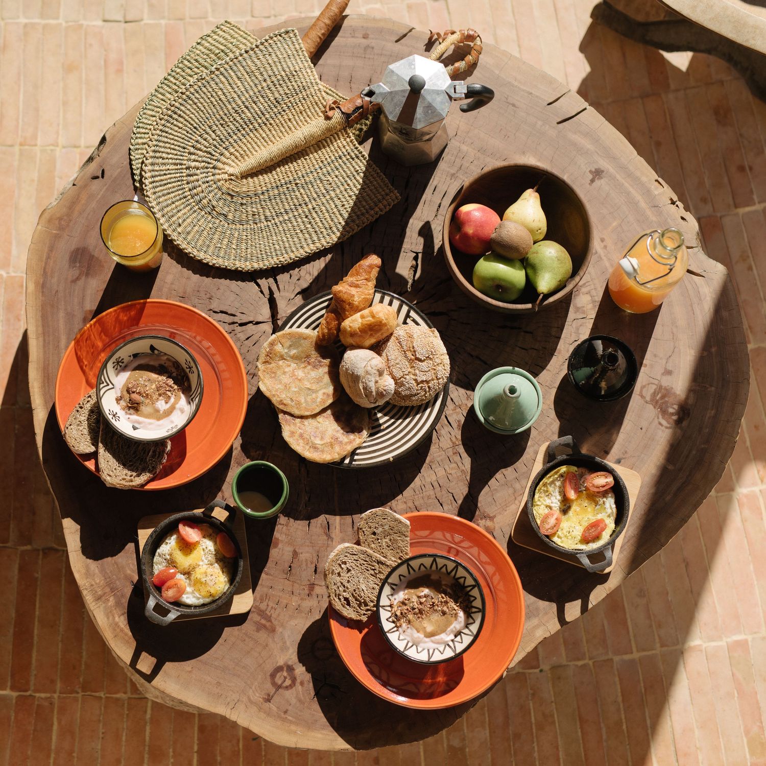 Overhead view of breakfast spread on round wooden table with various dishes and drinks.