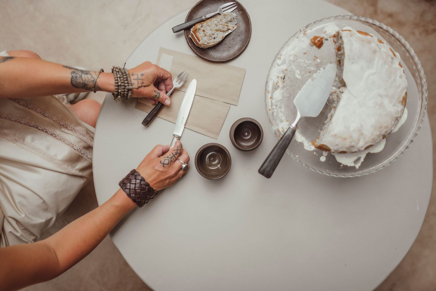 Overhead view of hands working with baking ingredients on a white table surface.