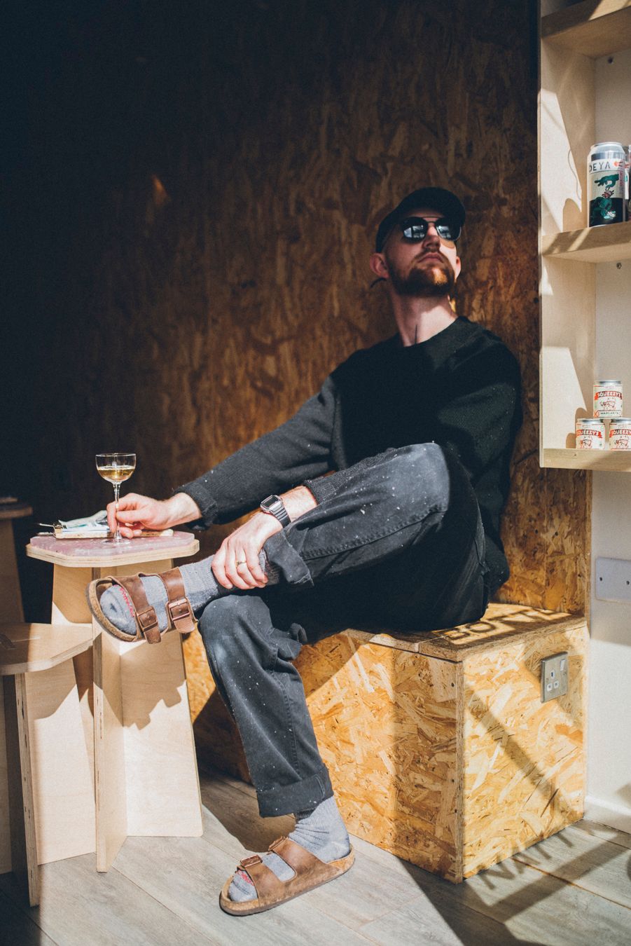 Casual dressed person relaxing with wine in industrial style shop interior.