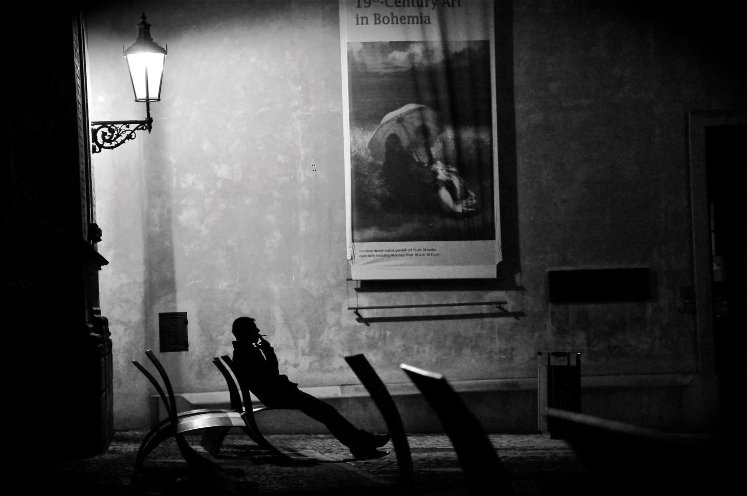 Dramatic black and white street scene with silhouettes and vintage lamp post.