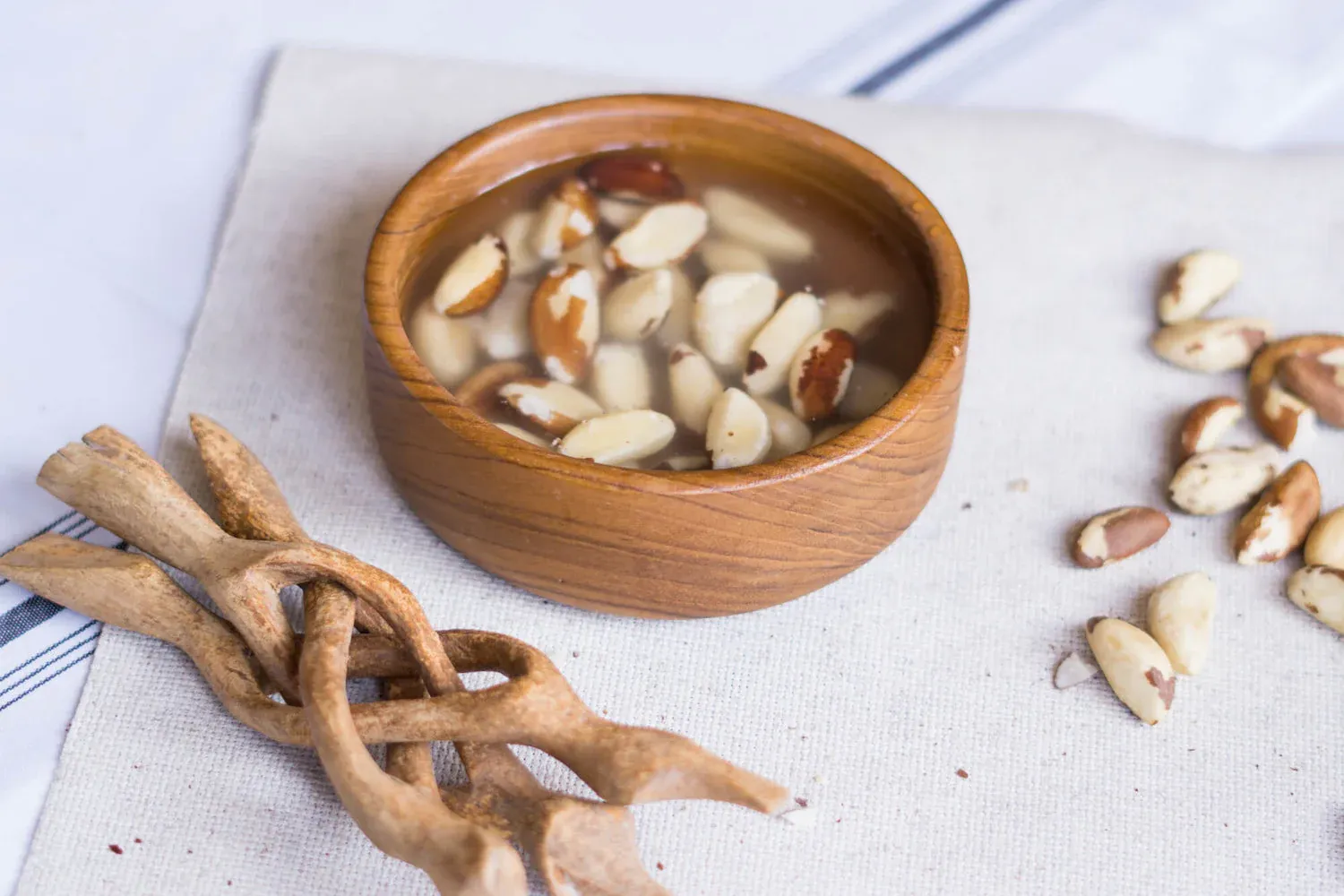 Sliced raw mushrooms being arranged in a bamboo steamer basket on a light surface for dim sum preparation.