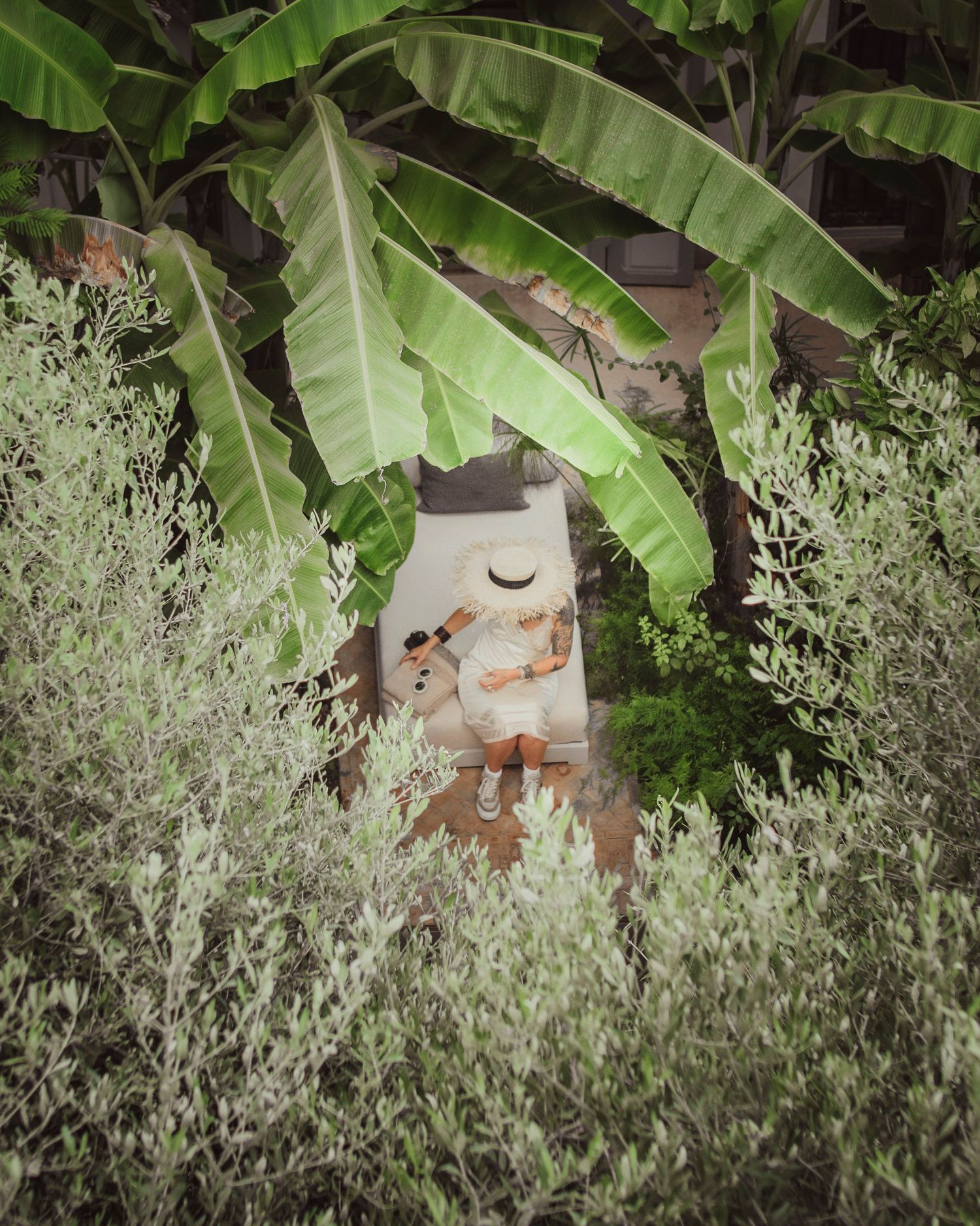 Decorative garden sculpture hidden among large banana leaves and lavender plants.