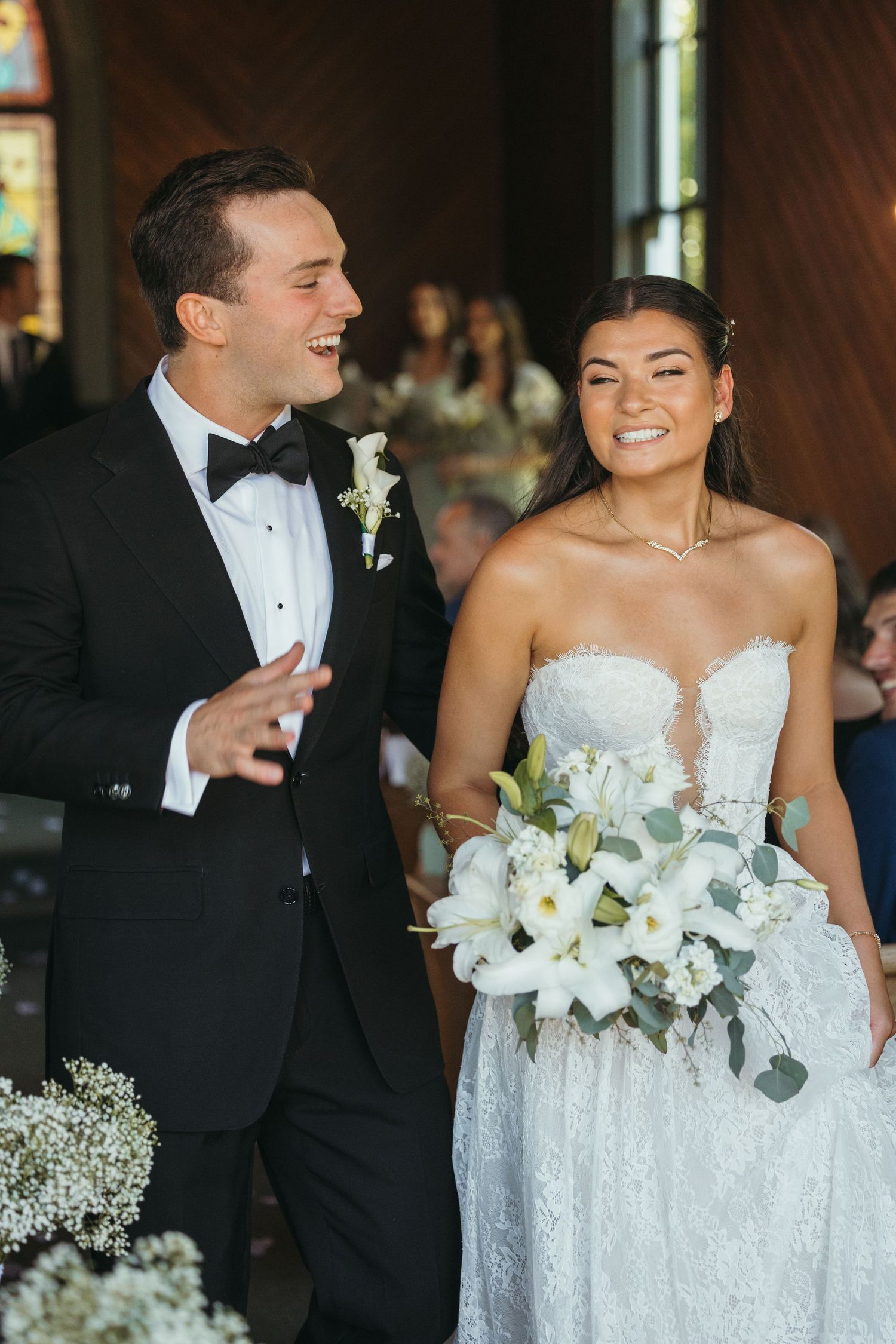 Bride in white lace dress and groom share joyful moments at wedding reception.