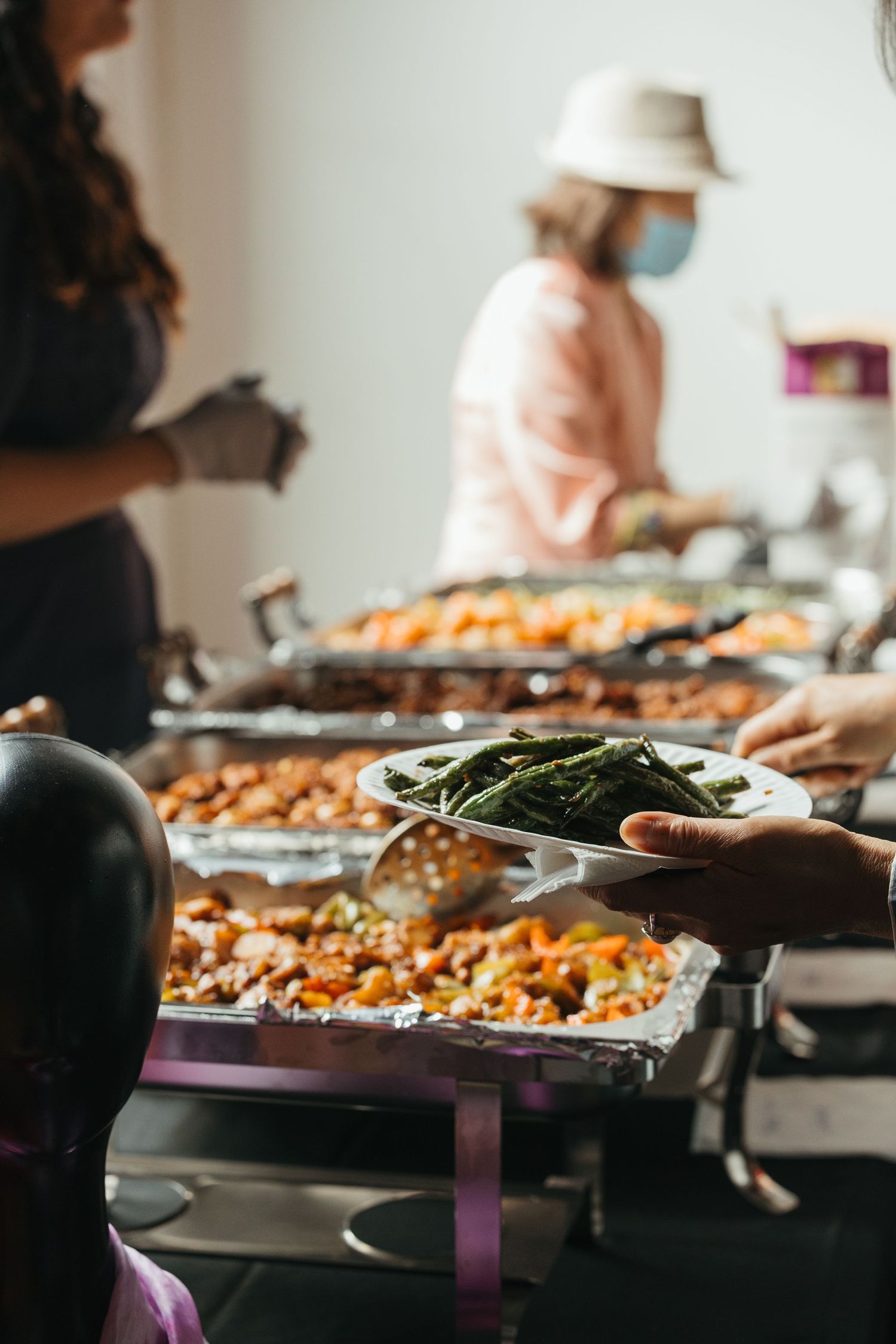 Catering buffet table with serving trays of food and green vegetables.