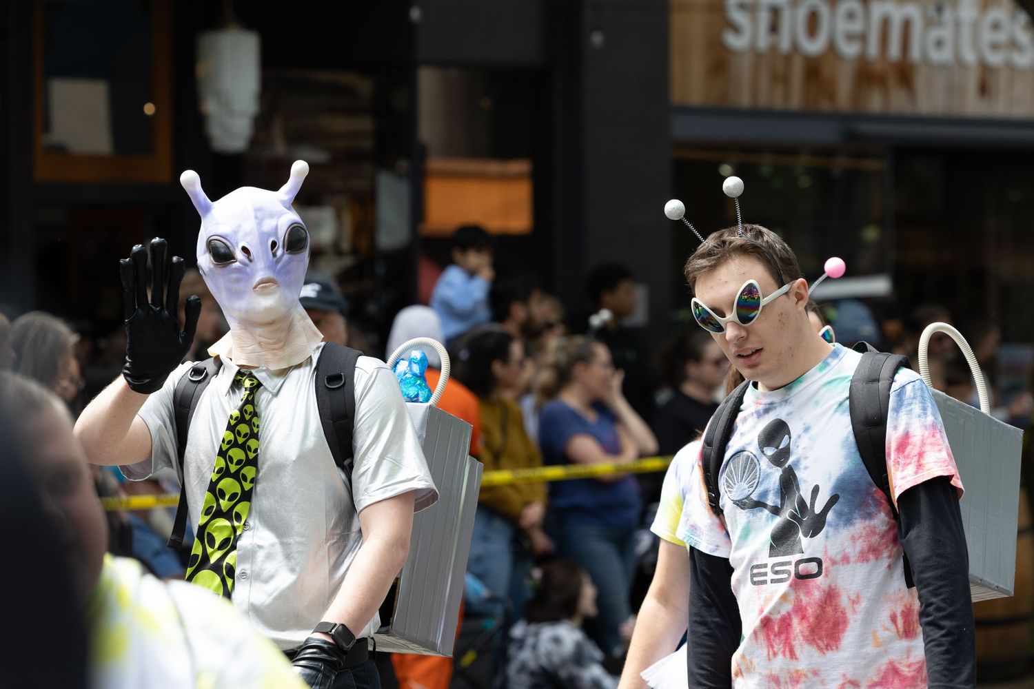 Street performers entertain crowd during urban festival with colorful costumes and props.