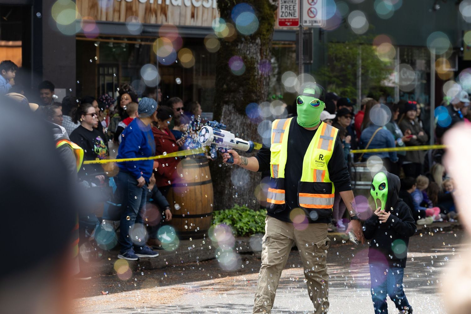 Water sprays over excited crowd during outdoor festival activities on urban street.