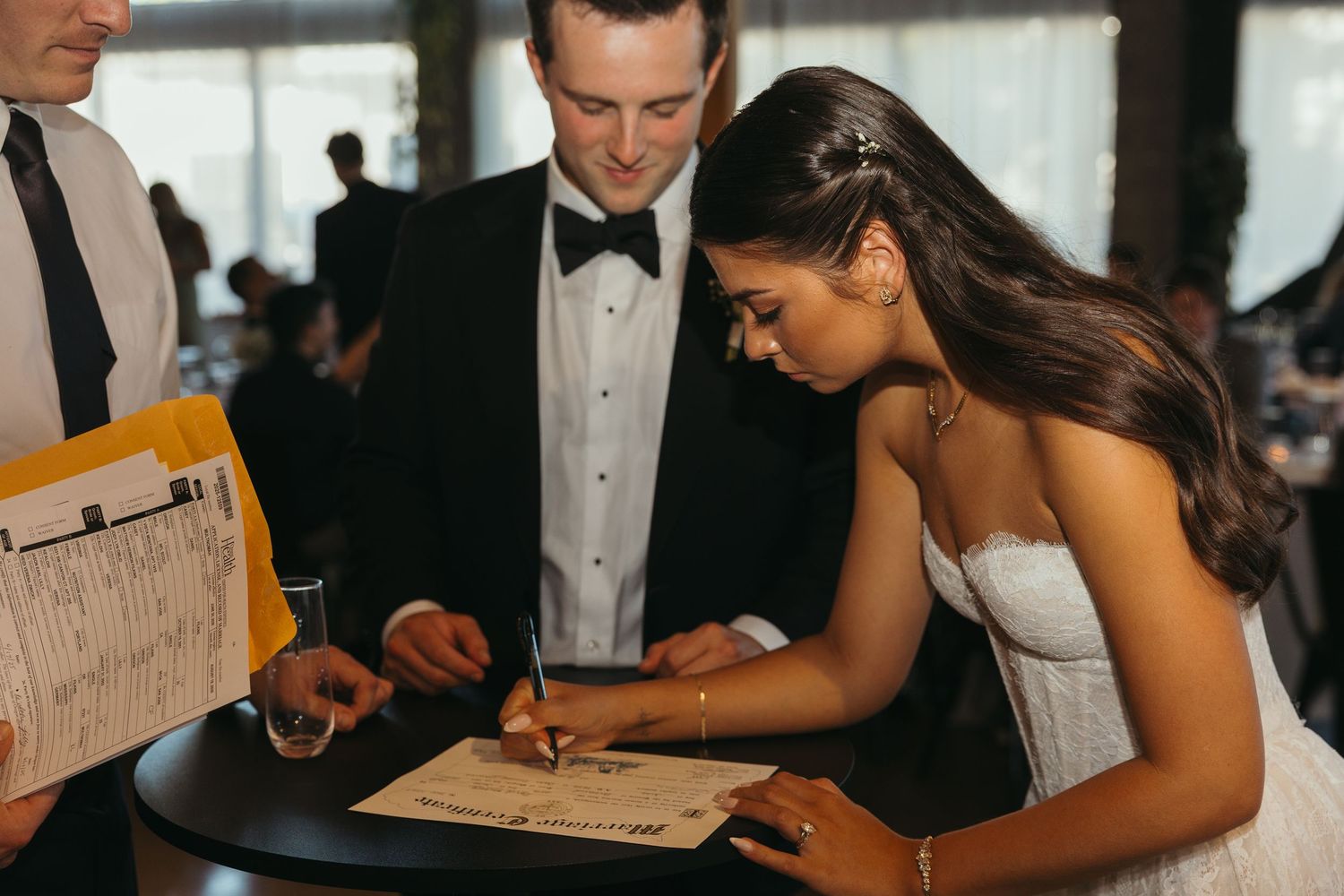 Couple signing marriage paperwork at their wedding reception.