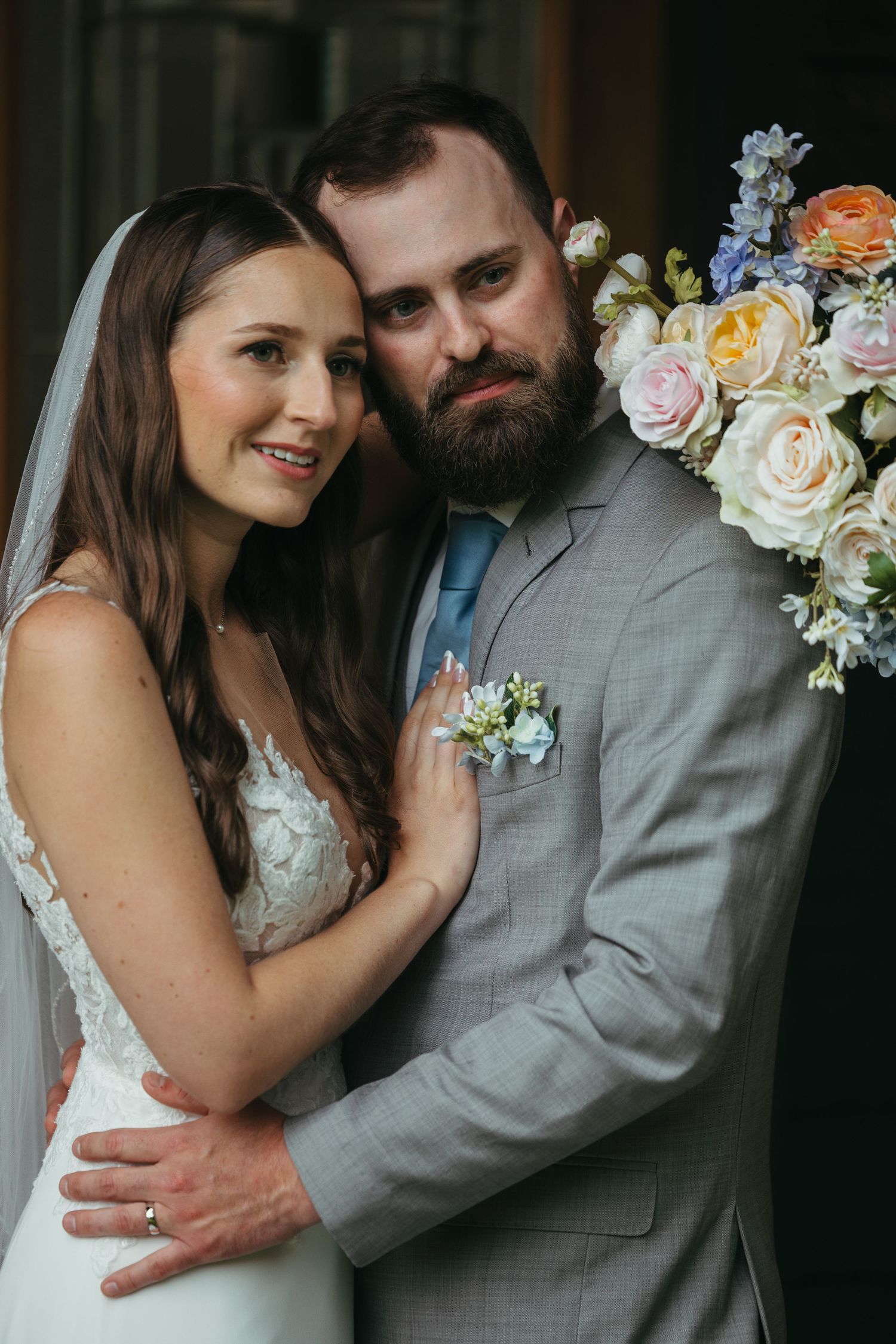 Tender moment captured between newlyweds with pastel floral accents.
