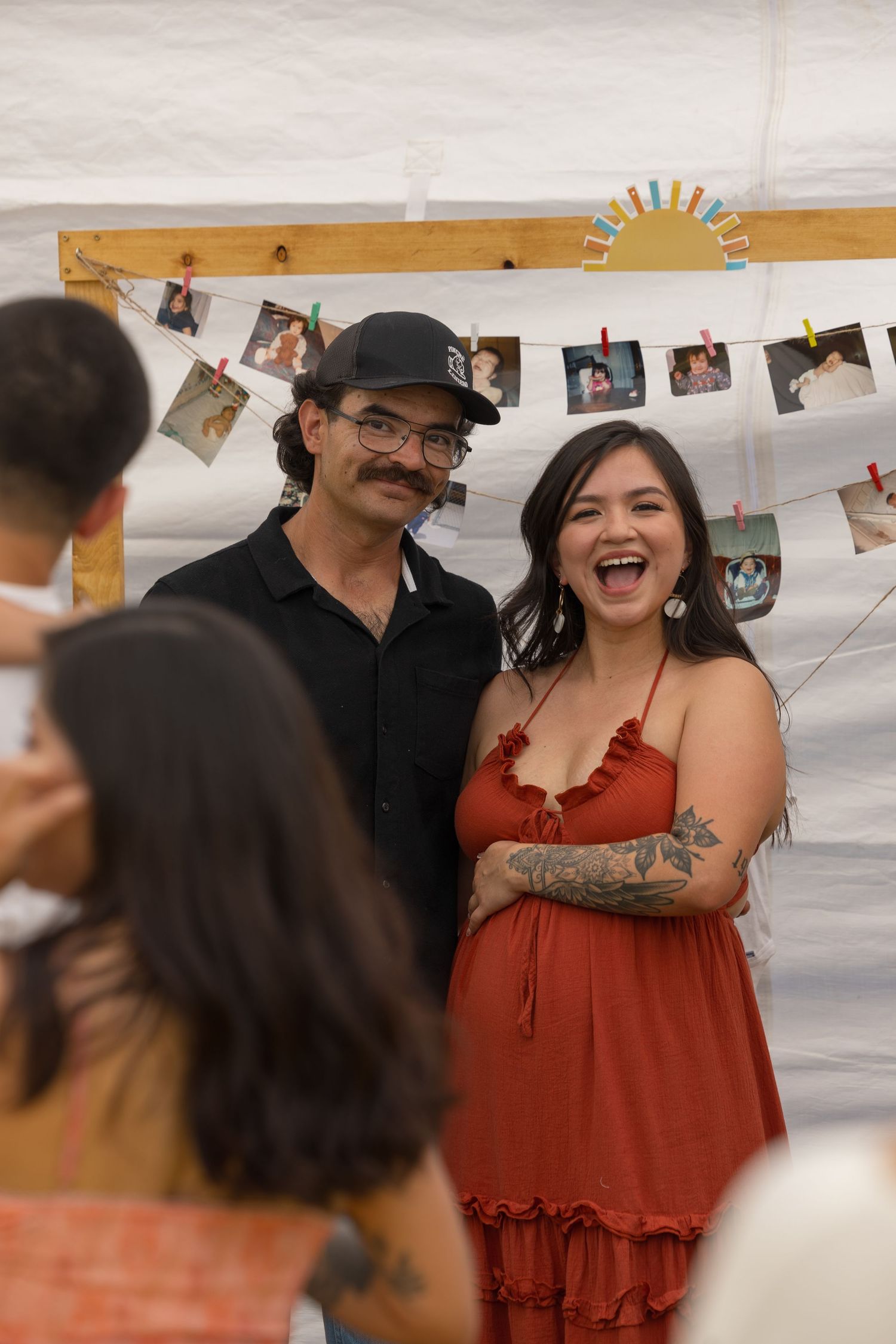 A group of people at a celebration or party with photos hanging on string lights in the background.