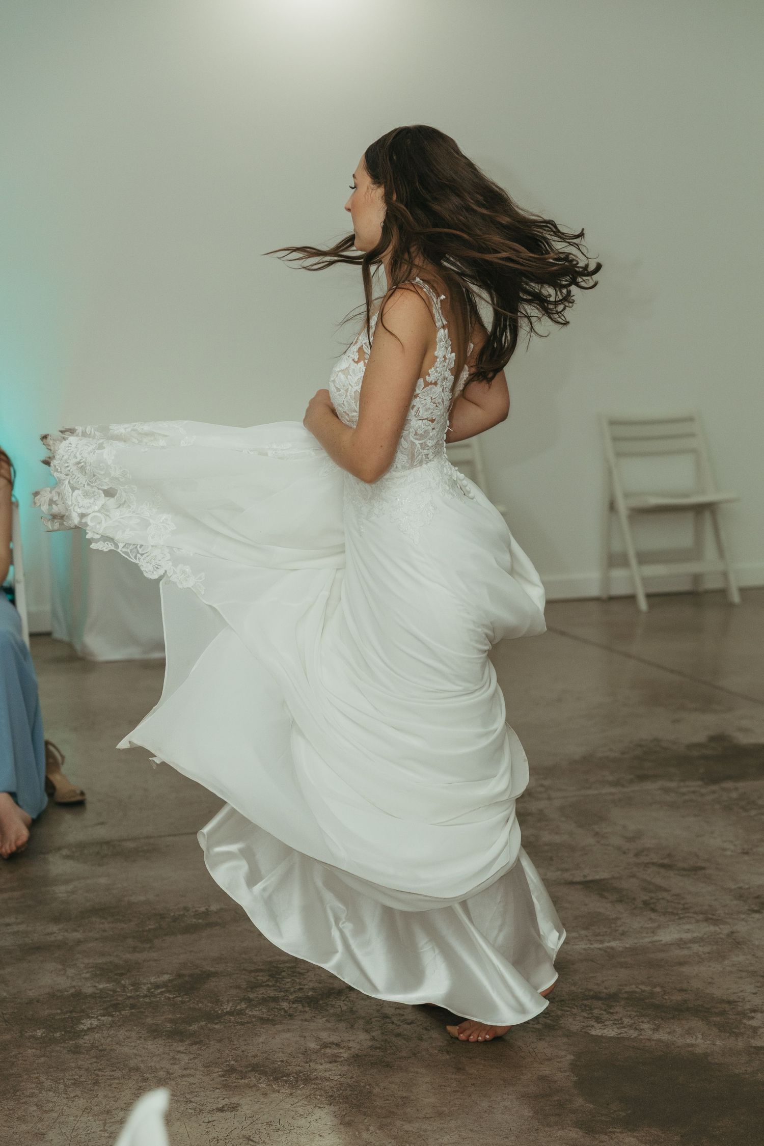 Bride twirls in her flowing white wedding dress on the dance floor.
