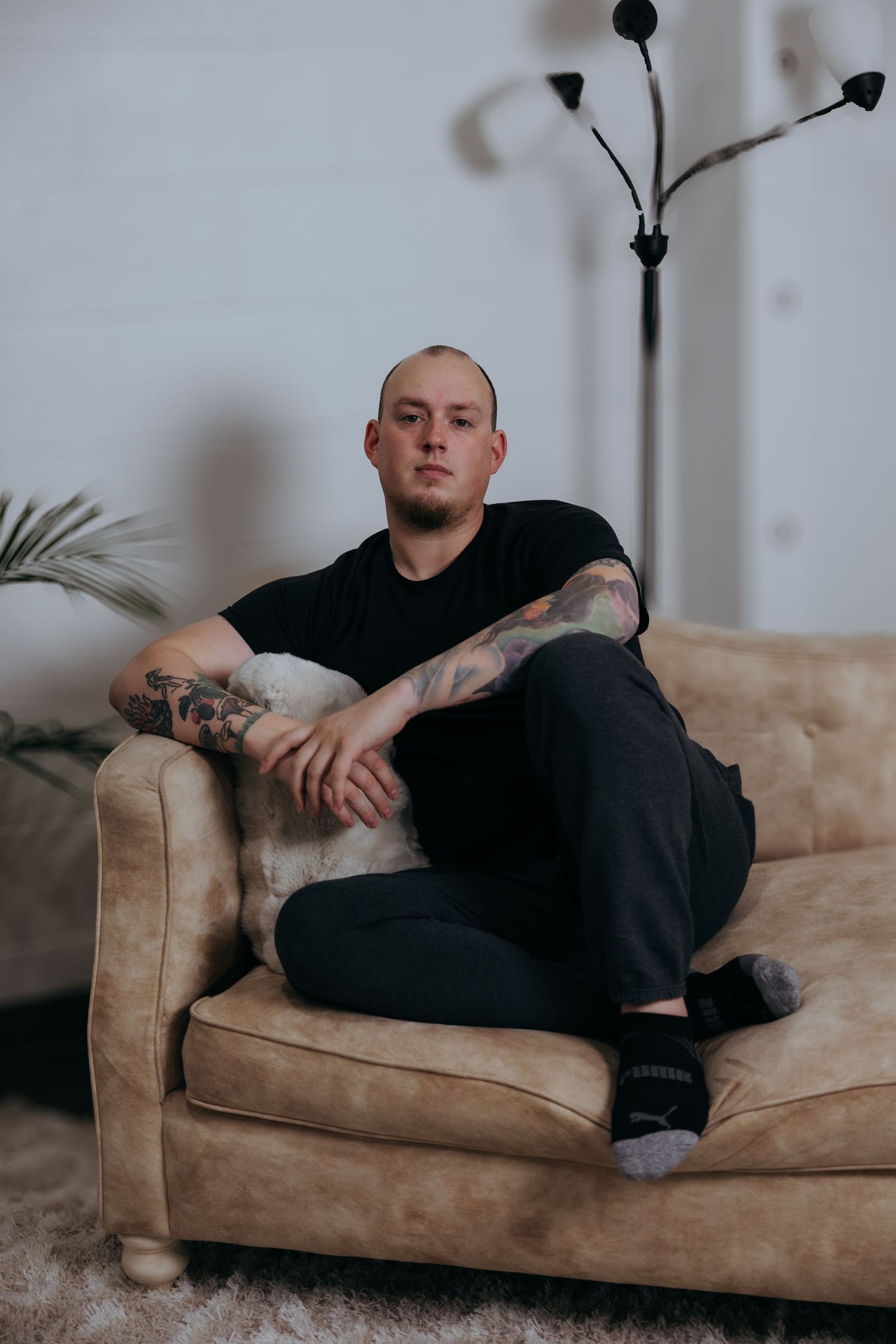 Person wearing black clothing relaxes on a tan leather couch in multiple reclining poses.