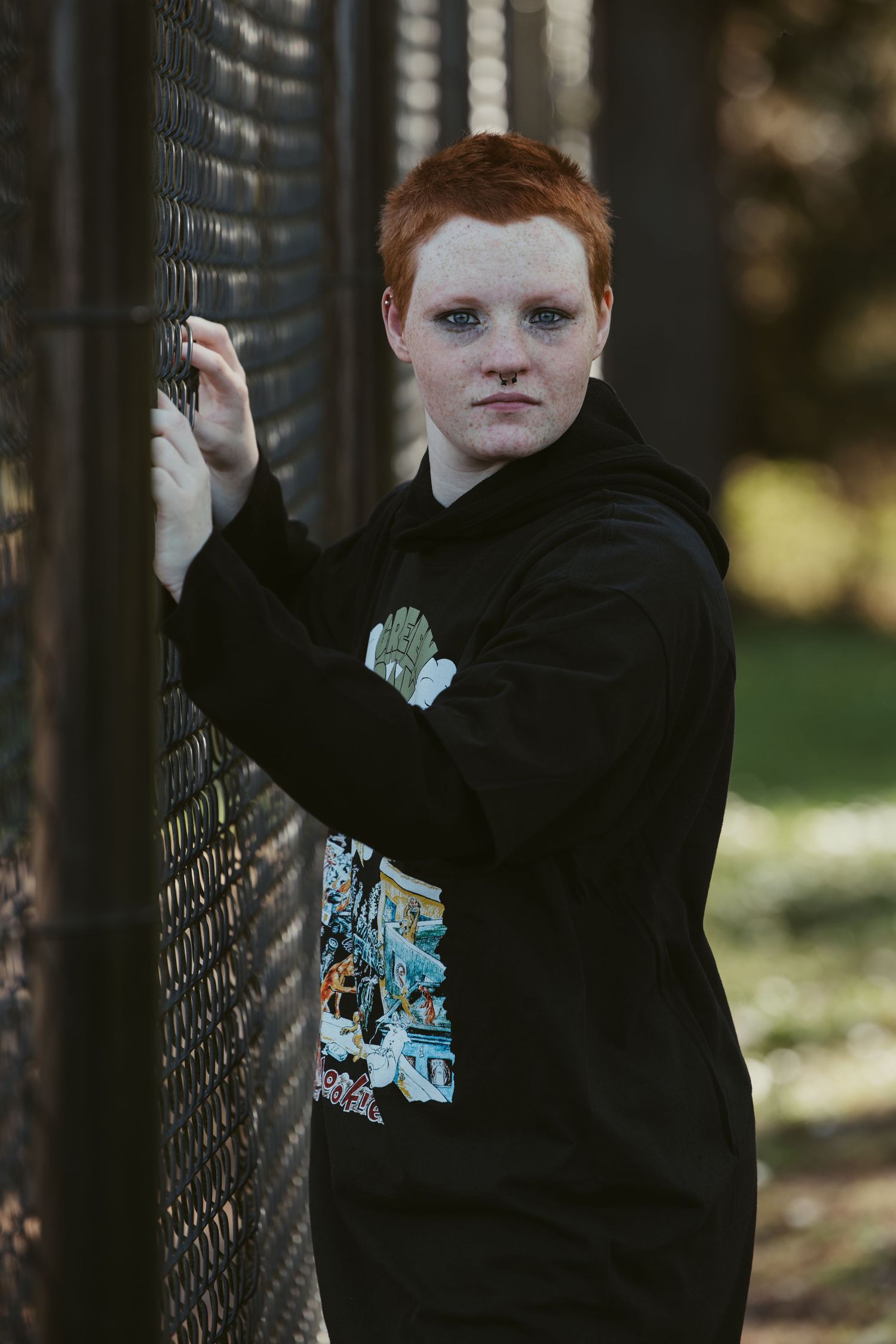 Young person in a black hoodie poses expressively against a dark fence in a sequence of candid shots.