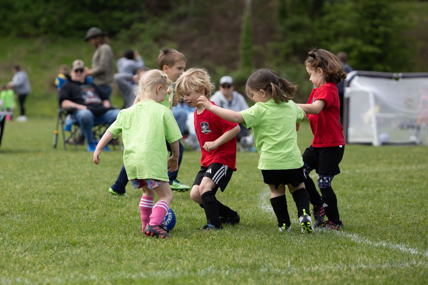 Children playing soccer on a sunny green field during an outdoor sports activity.