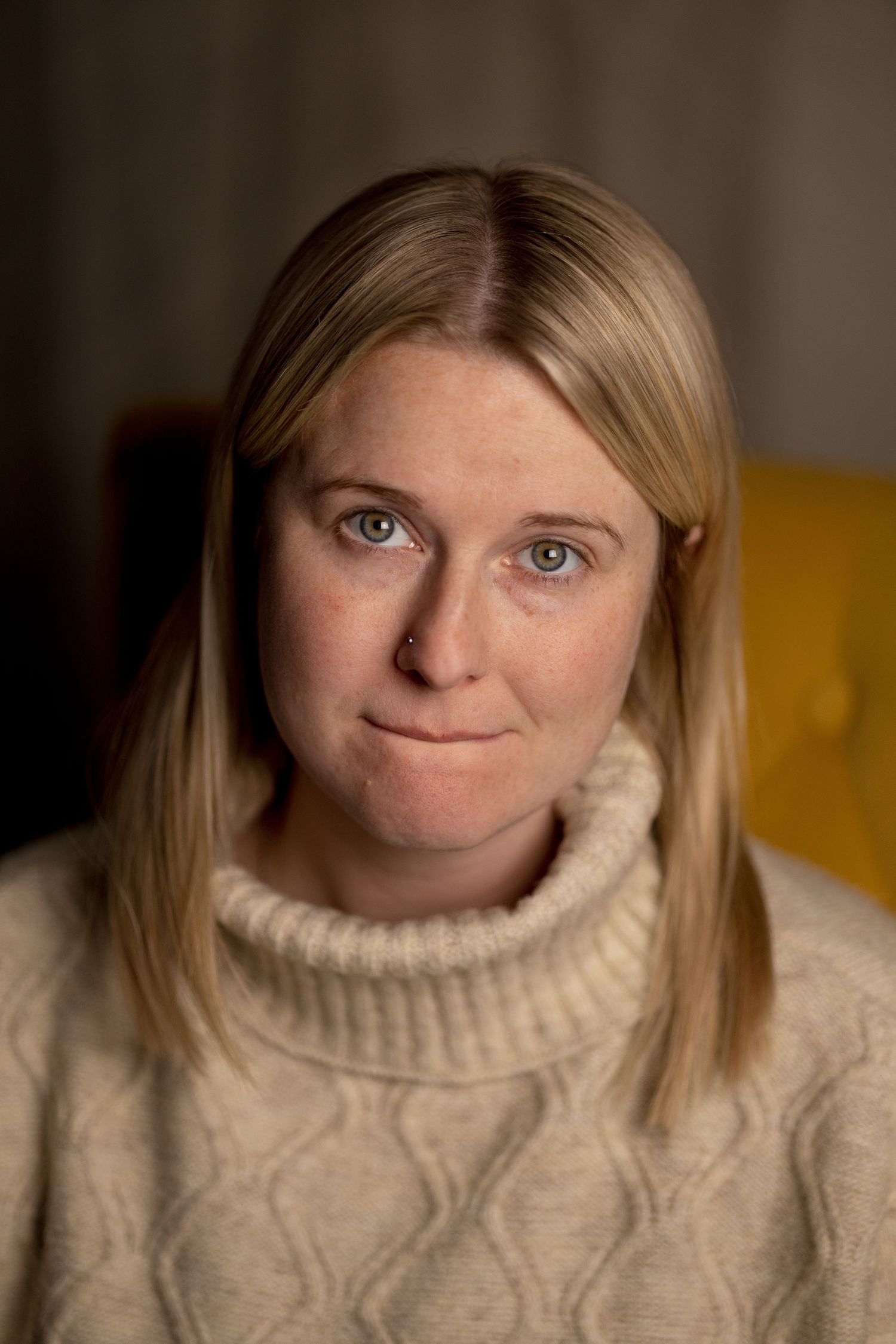 Close-up portrait in warm lighting showing someone wearing a cream cable knit sweater.