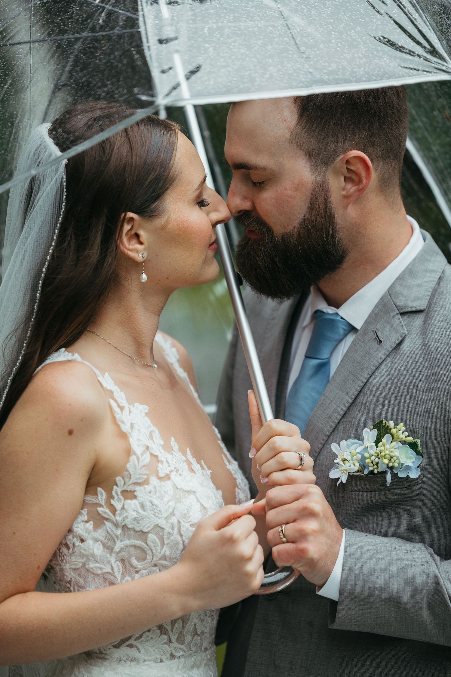 Romantic moment under clear umbrella during wedding photoshoot.