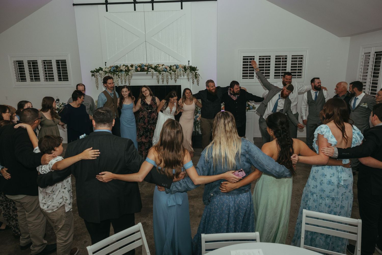 Wedding guests form a circle on the dance floor during reception celebrations.