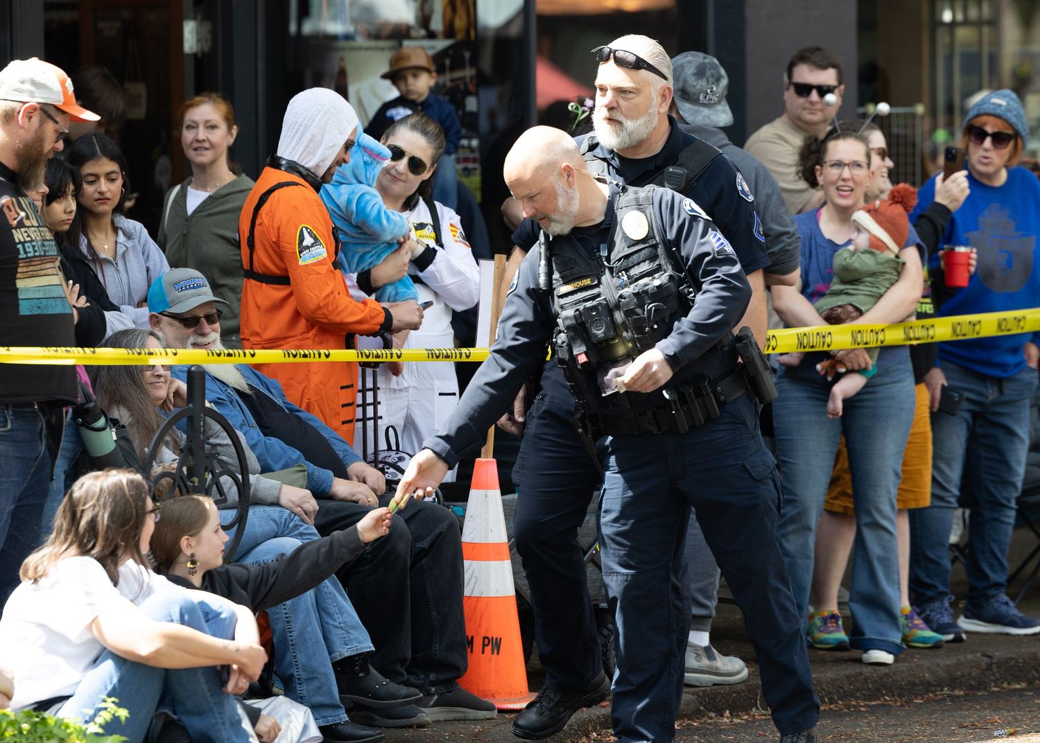 Police officer provides security at a crowded public event with spectators behind barriers.