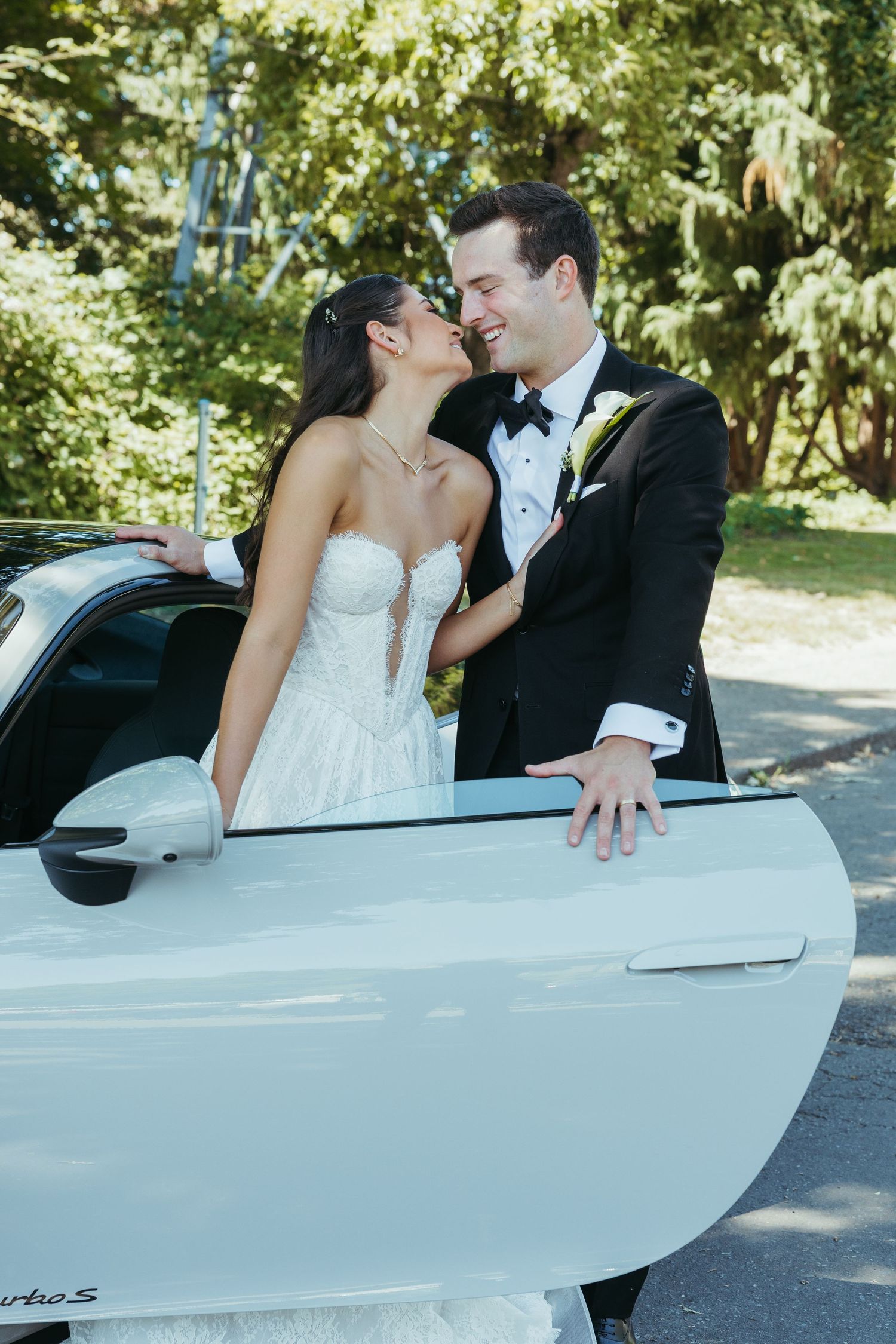 A romantic moment by a white car during a wedding photoshoot.