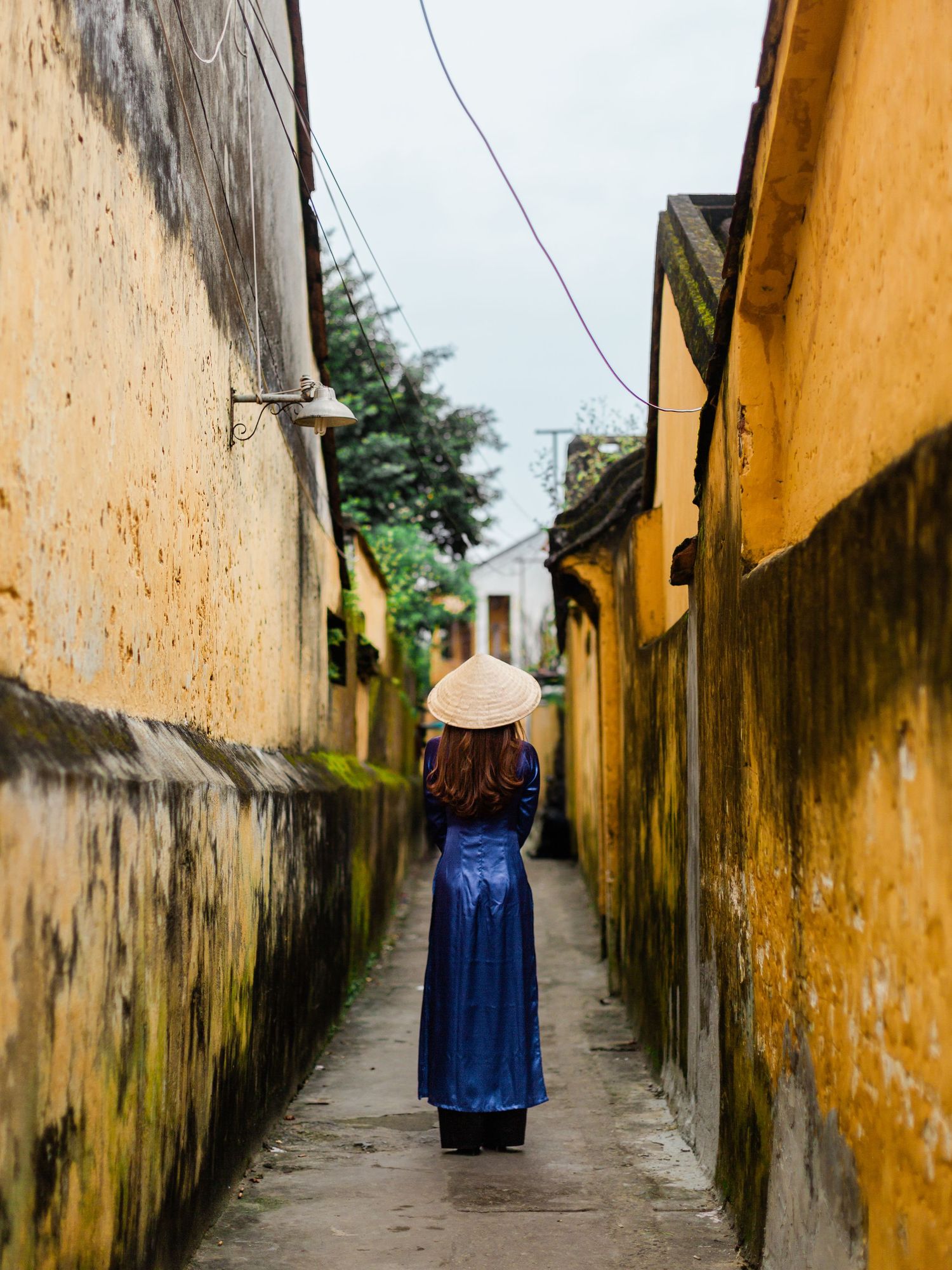 Narrow alley with weathered yellow walls in an old Asian town.