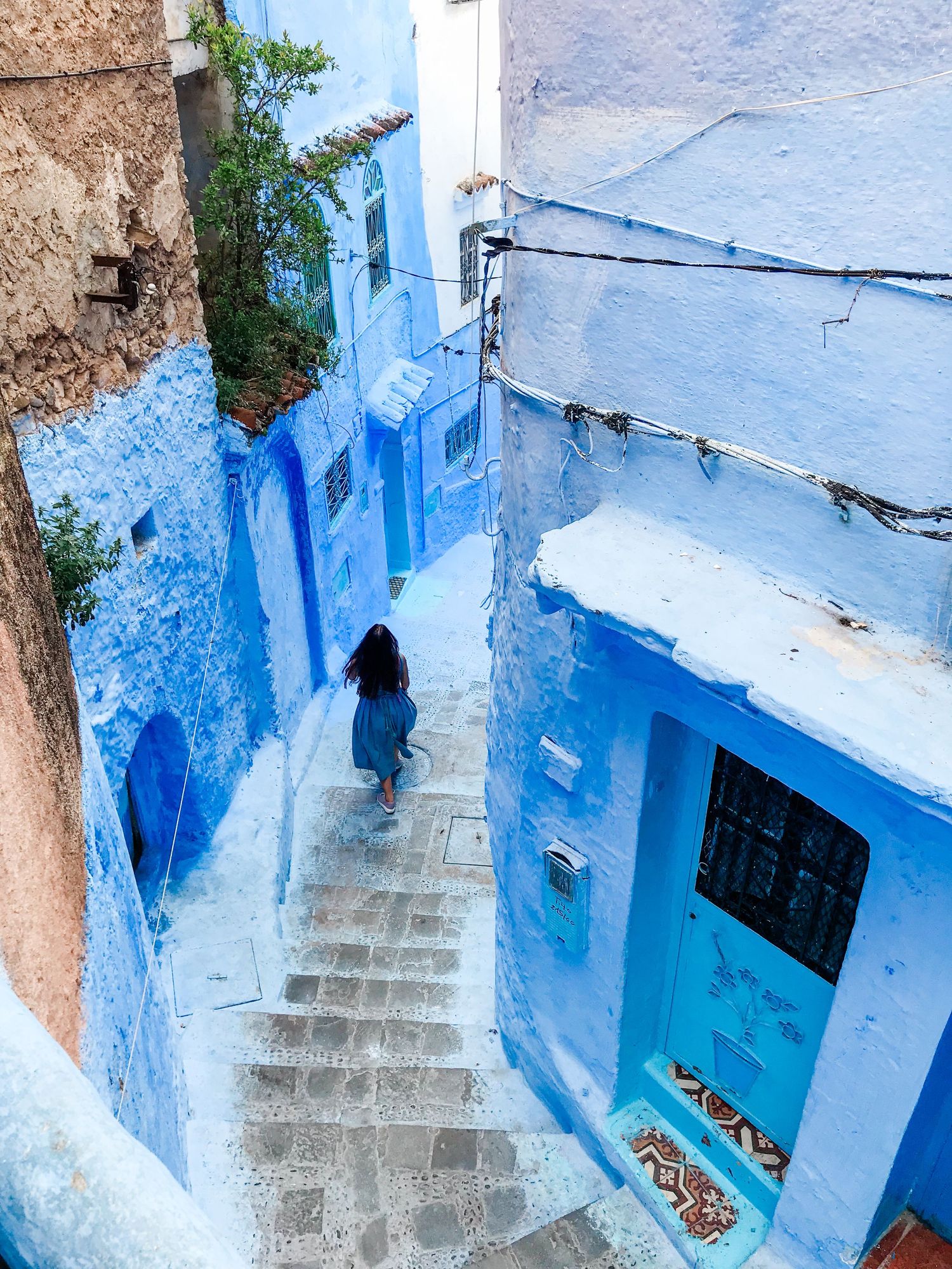 Stone steps winding through blue-washed walls in a traditional Moroccan street.