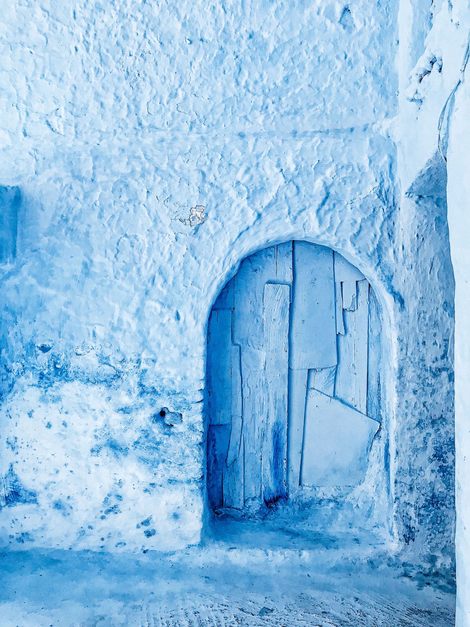 Series of blue painted archways and walls creating a monochromatic tunnel effect.