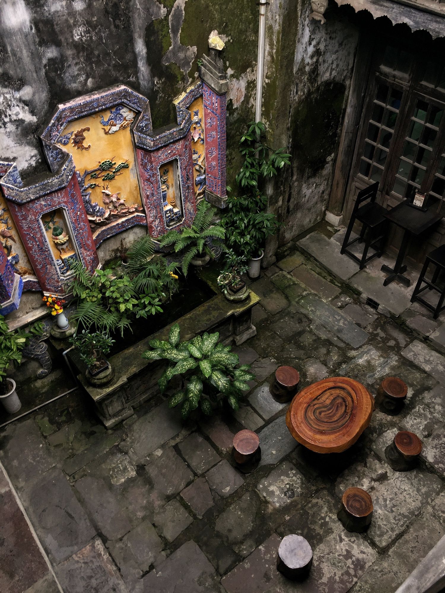 Aerial view of a decorative Asian courtyard with stone floor and potted plants.