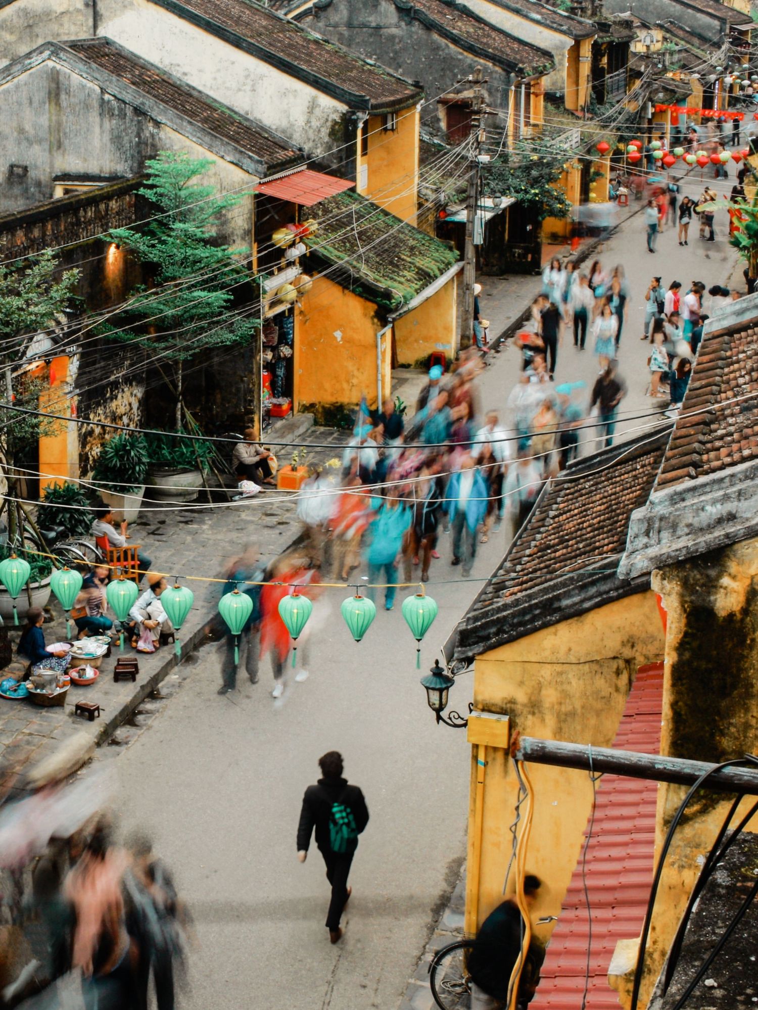 Bustling street scene with motion blur of people walking through yellow buildings in ancient town.