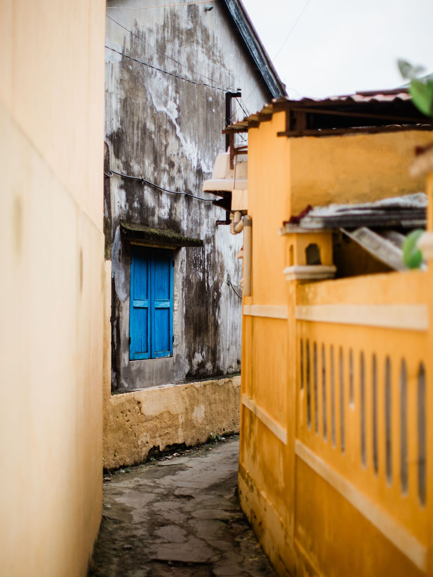 Narrow alley between yellow and weathered walls with a bright blue door in an old town.