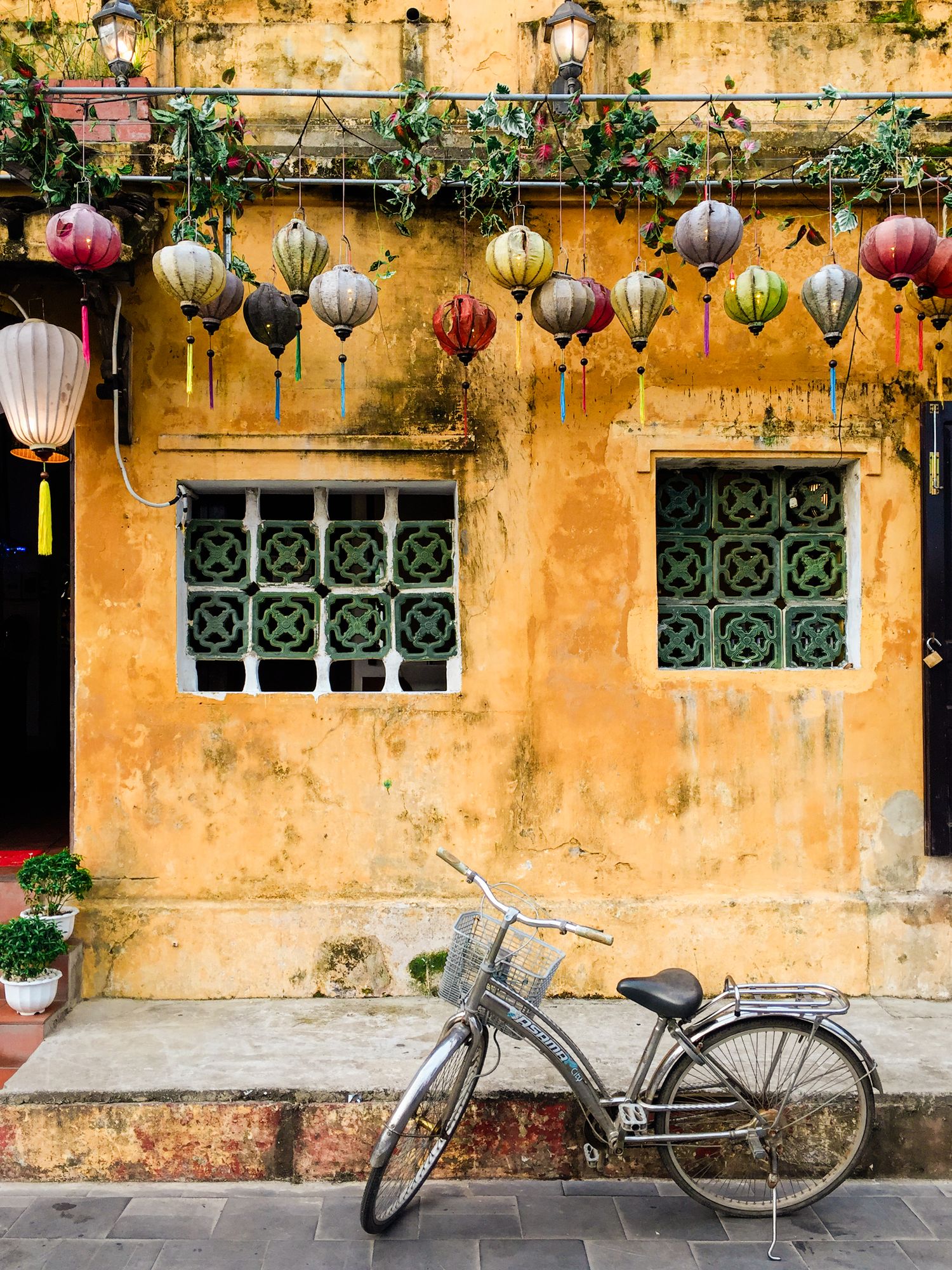 Vintage bicycles parked against yellow wall with hanging lanterns and ornate windows.