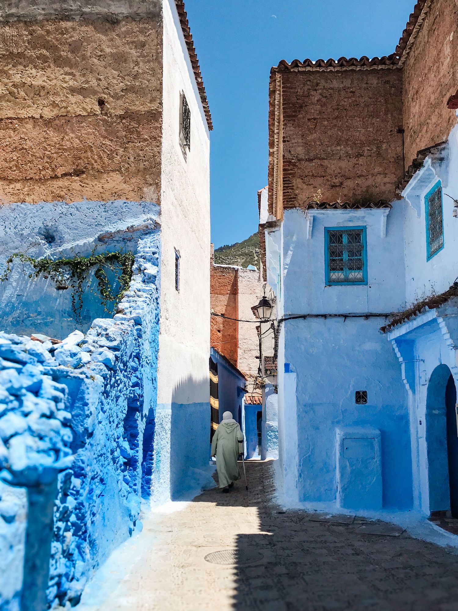 Narrow alleyway with white and blue painted walls in a traditional Moroccan medina.
