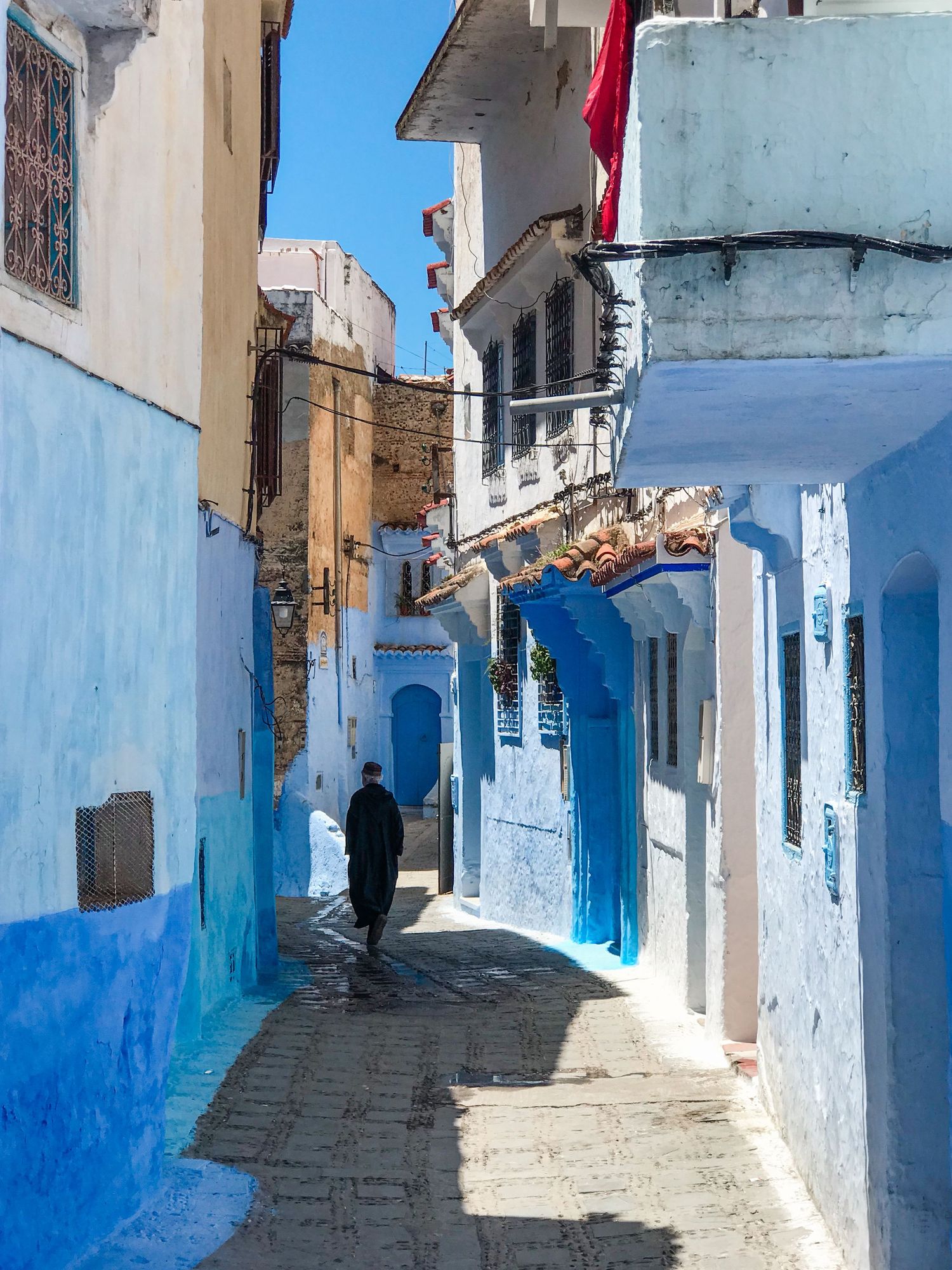 White and blue painted alleyway with traditional architecture in Chefchaouen's old town.