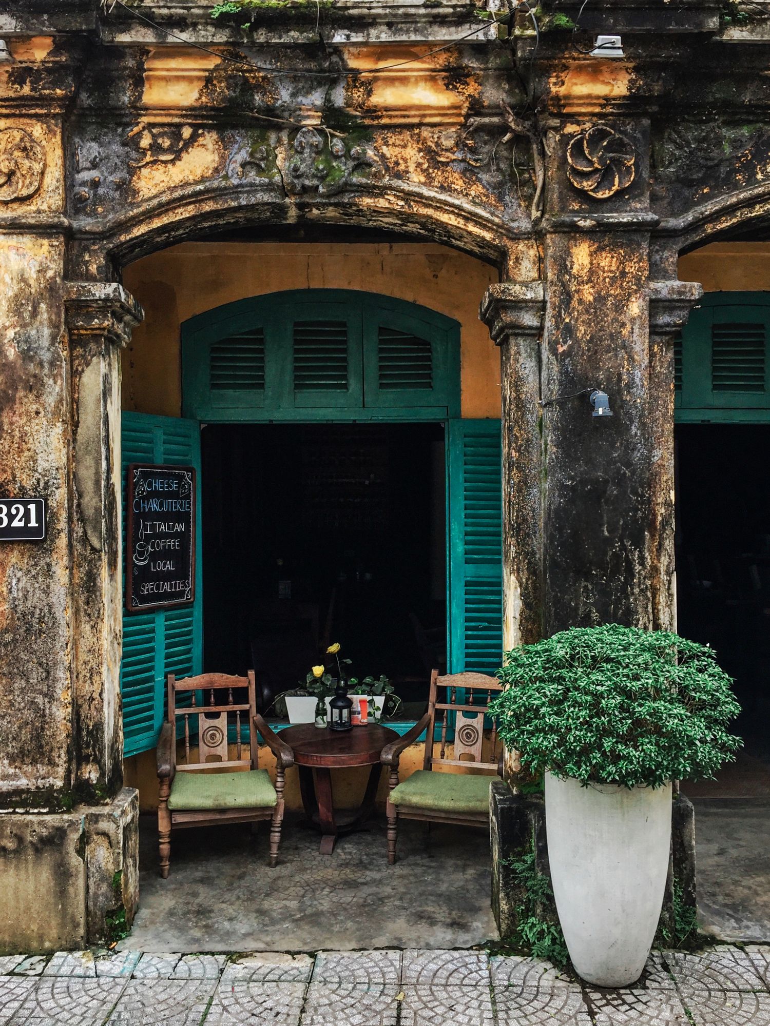 Vintage colonial architecture with turquoise shutters and ornate details in an Asian street cafe.
