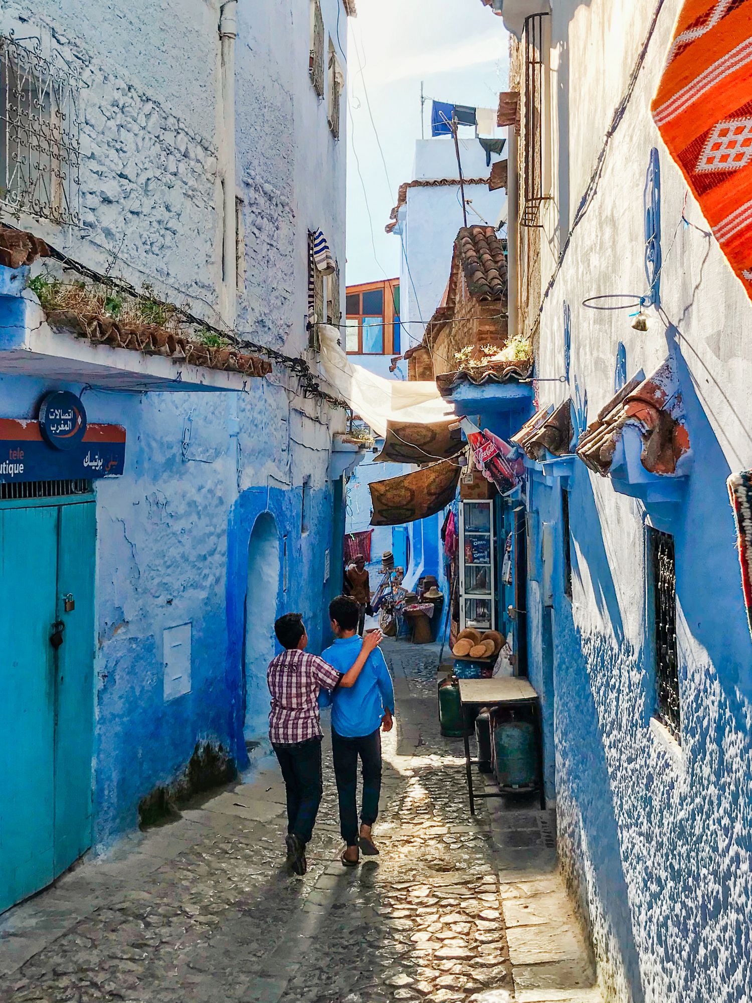 Tourists walking through blue and white painted alleyways in Chefchaouen, Morocco.