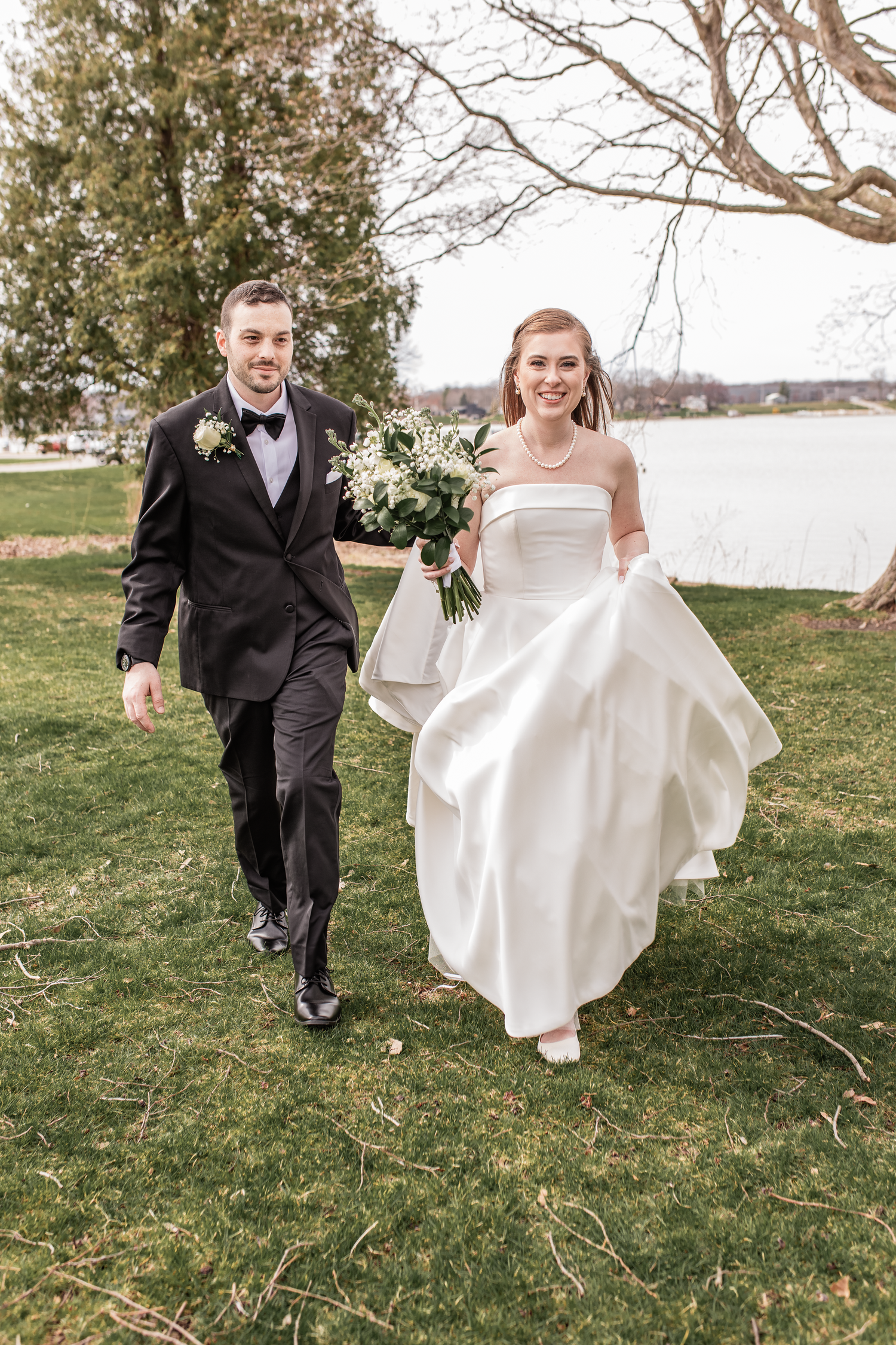 Smiling bride and groom walk outdoors near a lake in grand rapids michigan, taekn by west side of stae photographer