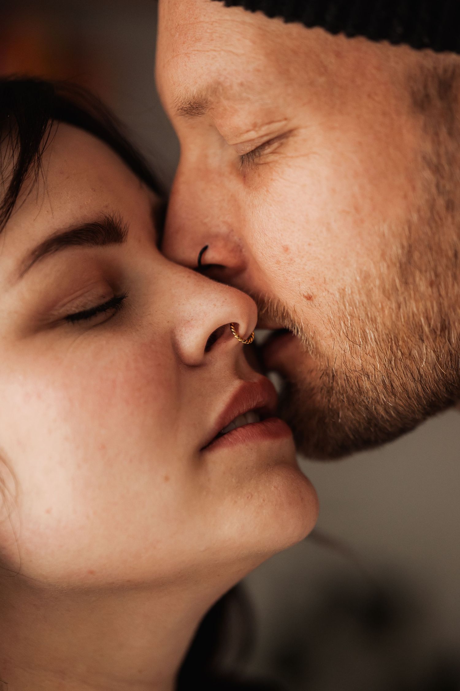 Close-up of a couple sharing a tender nose kiss with eyes closed, expressing love and intimacy.