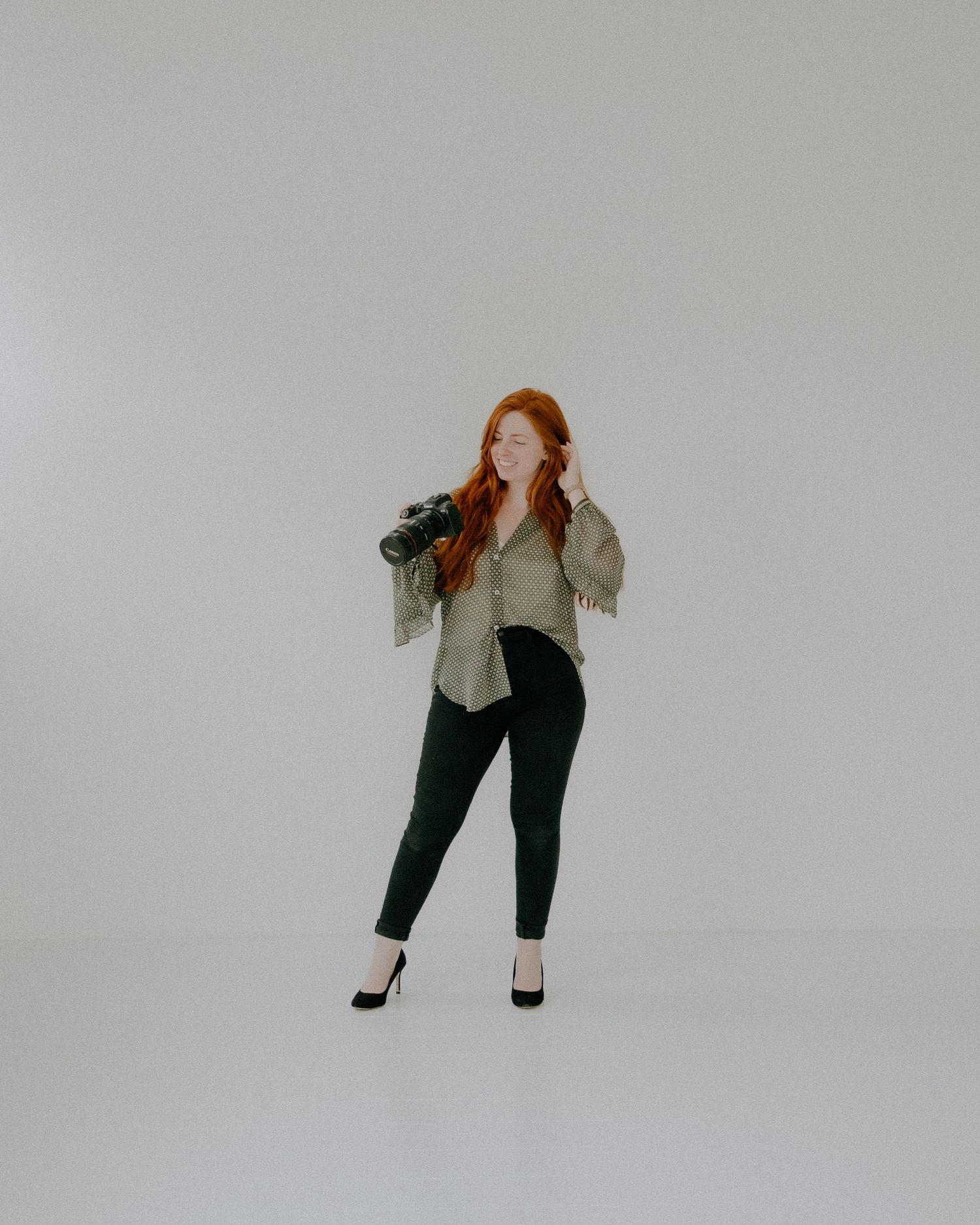 Studio portrait of someone in business casual attire posing against grey background.