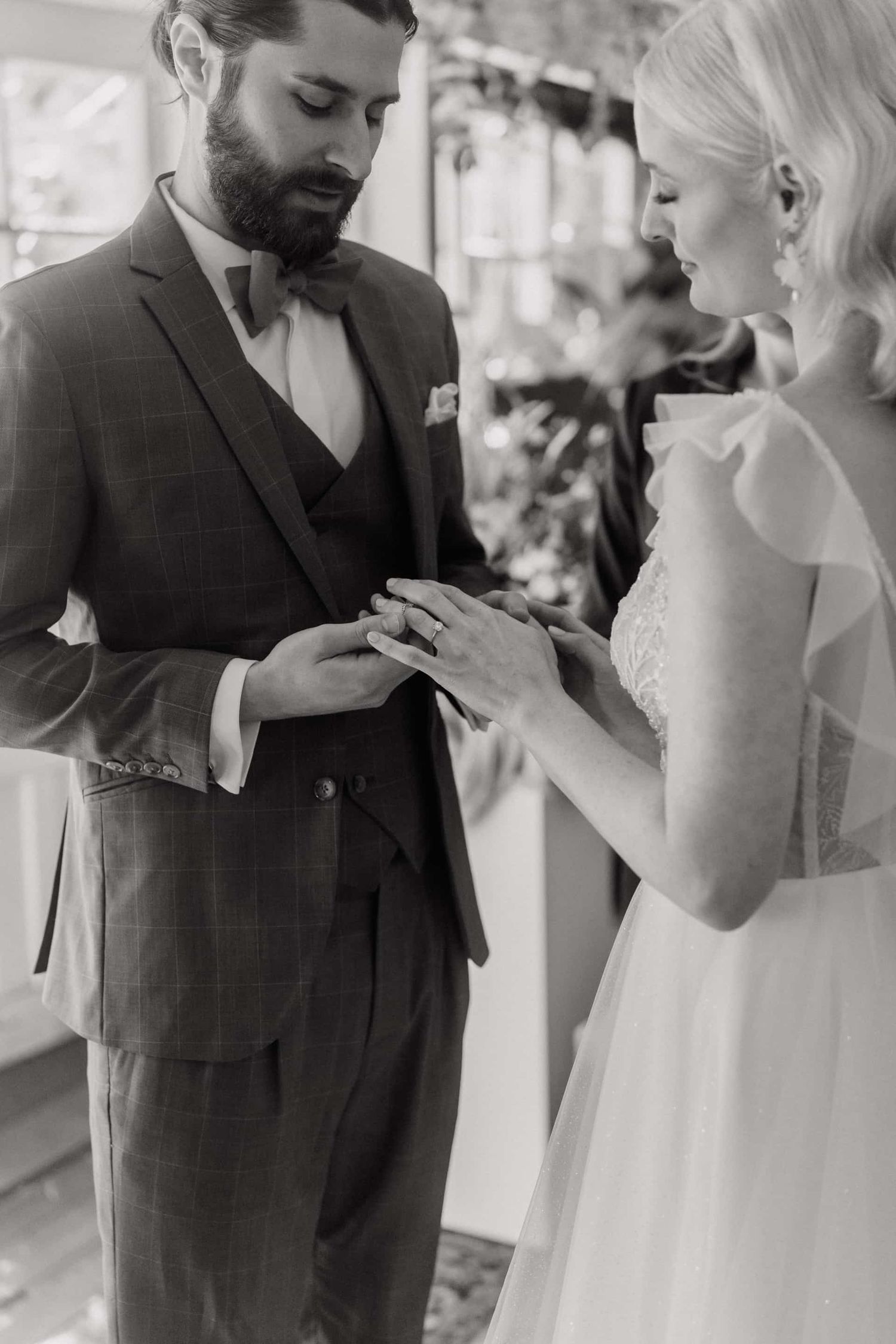 A tender black and white wedding moment as a couple exchanges rings during their ceremony.