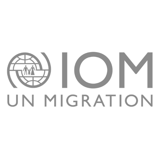 IOM UN Migration logo in gray, featuring a globe icon with two figures and bold IOM lettering.