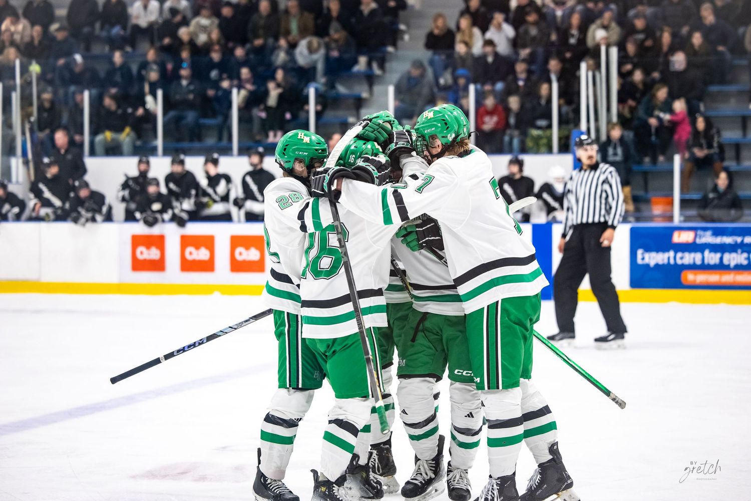 Hill-Murray Pioneers hockey players celebrating a goal together on the ice during a game.