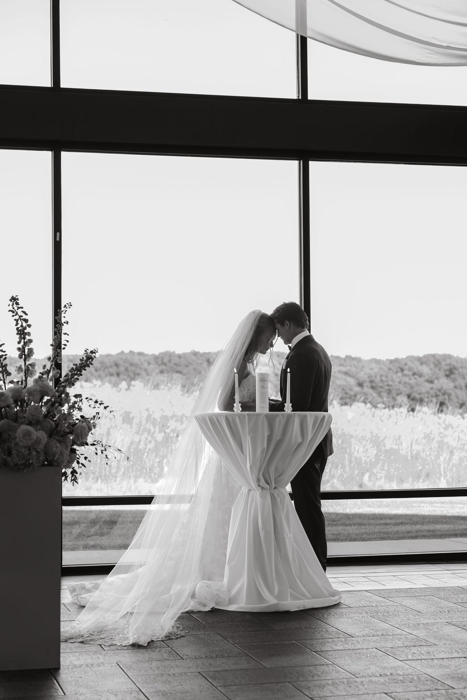 Black and white photo of bride and groom at unity candle ceremony.